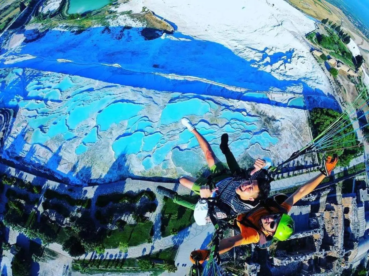 Pamukkale paragliding in Turkey: soaring high above the magnificent white travertine terraces and striking turquoise thermal pools, capturing their unique aerial beauty from above.