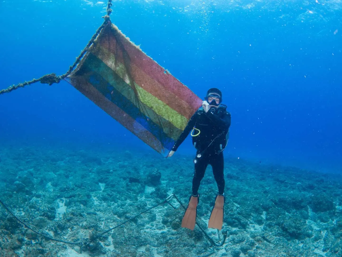 屏東小琉球FUN DIVE潛水活動，潛水員在海底與色彩繽紛的旗幟合照，記錄美好水中時光。
