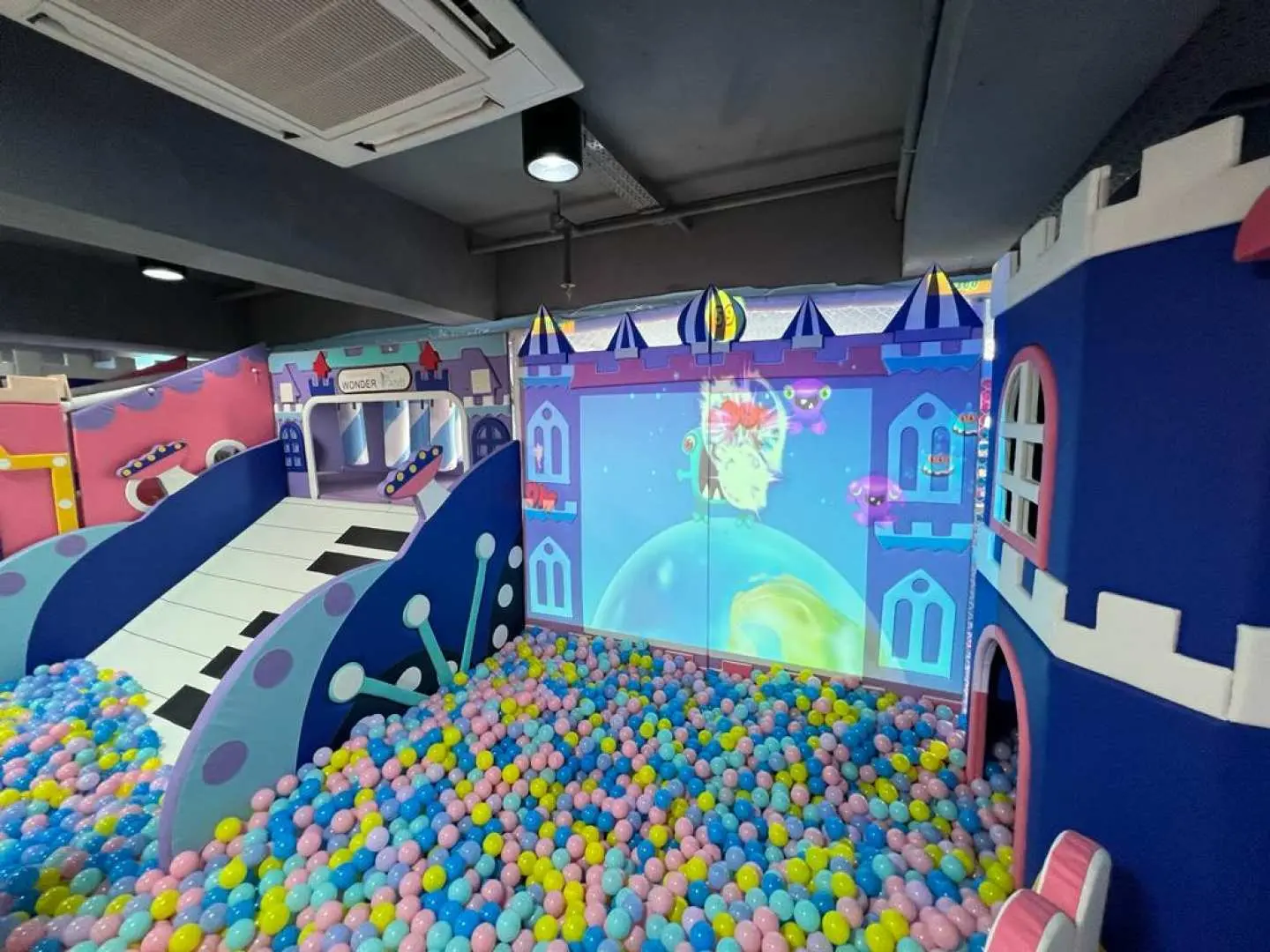 葵興WeMoment Wonderland室內遊樂場嘅城堡主題波波池，牆面設有互動投影，旁邊仲有鋼琴造型滑梯，為0-6歲小朋友打造充滿想像嘅玩樂空間。