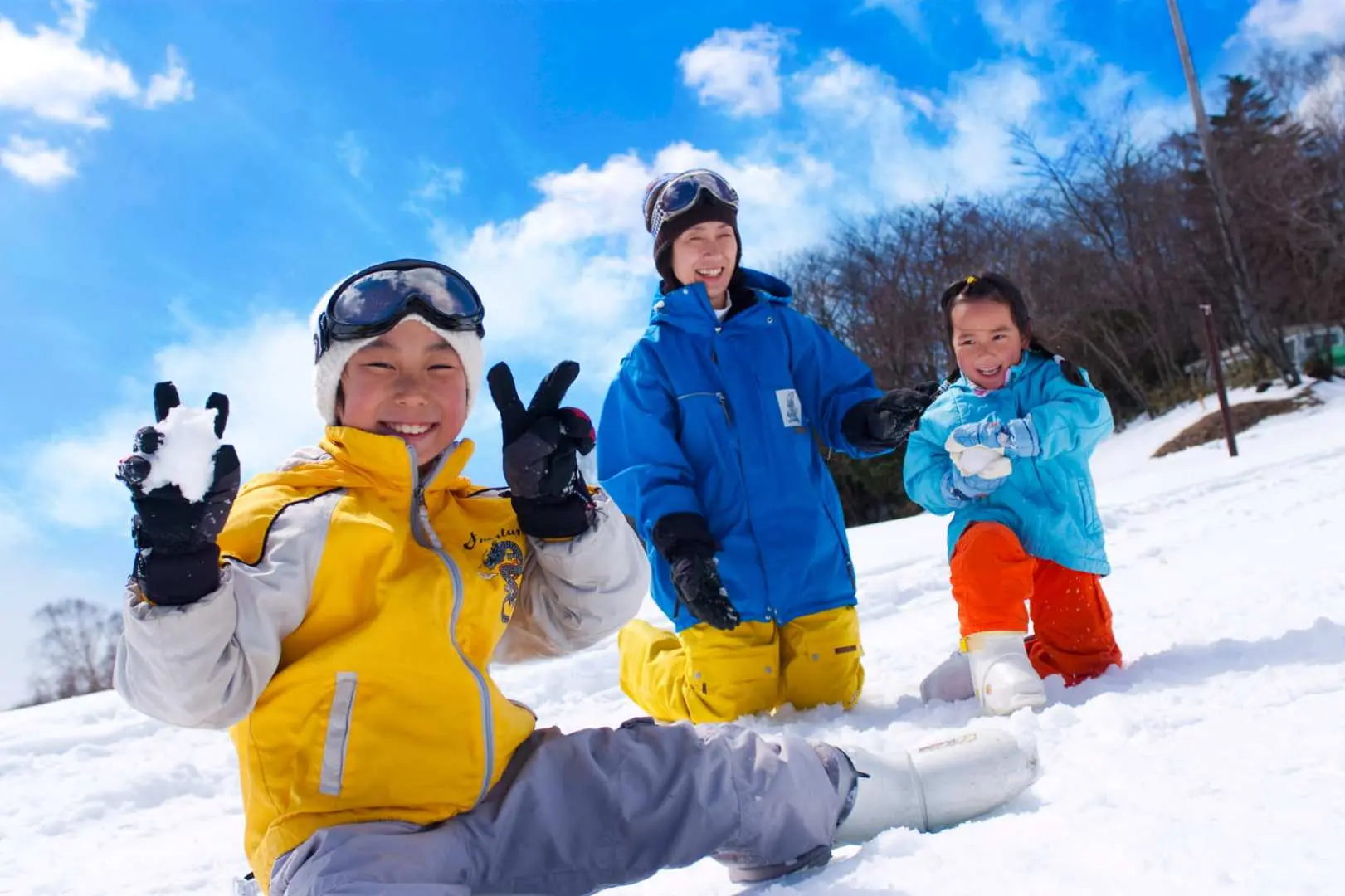 兩位孩童與一位大人在富士山YETI滑雪場的雪地中玩耍，小孩開心地展示雪球，享受打雪仗的歡樂時光。