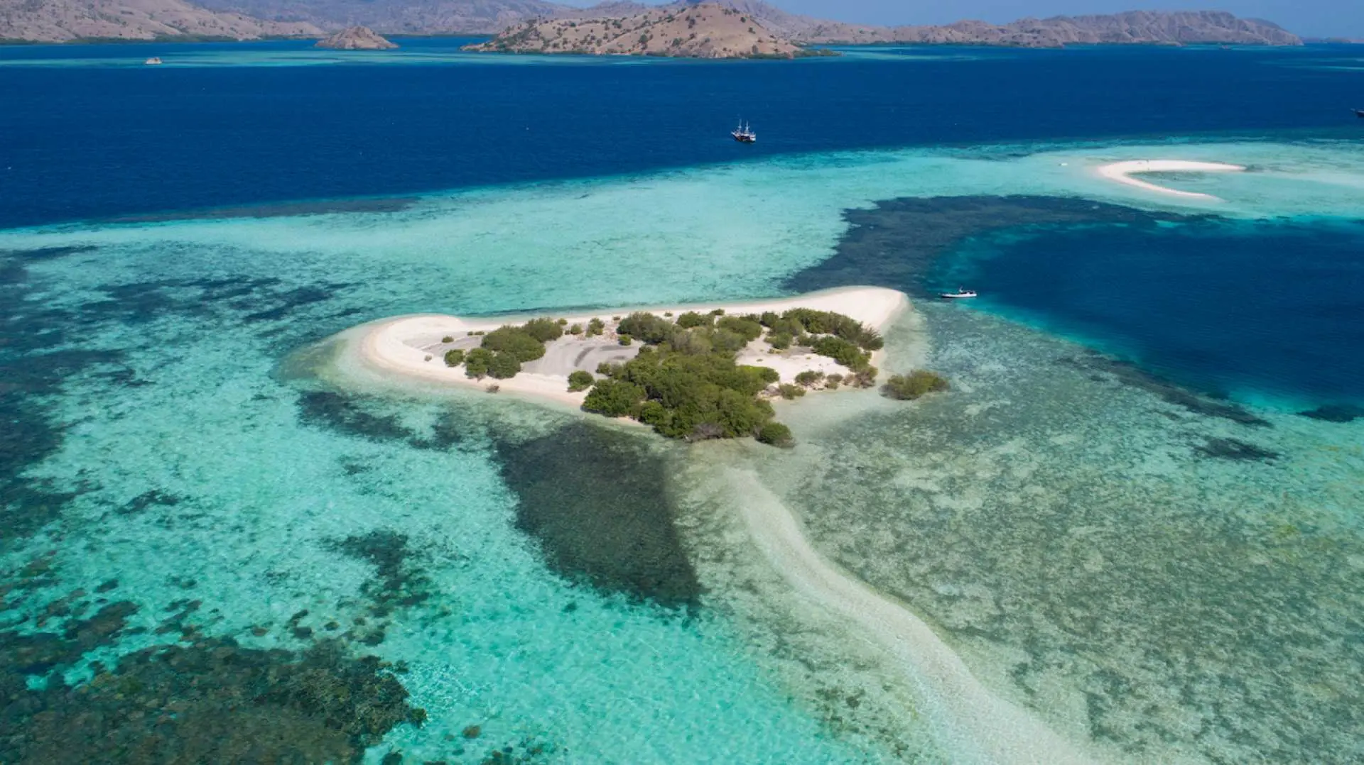 Aerial view of Taka Makassar sandbar in Komodo National Park, Indonesia, surrounded by crystal-clear turquoise waters, ideal for snorkeling and water activities on a Komodo Island day tour.