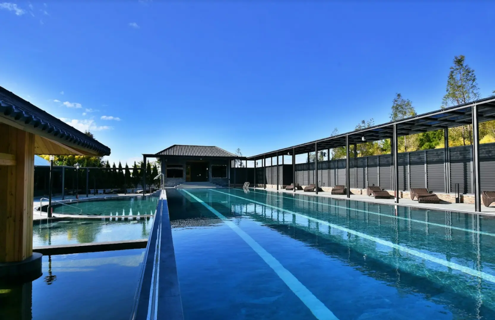 苗栗享沐時光莊園渡假酒店寬闊的戶外溫泉泳池，蔚藍池水在晴空下閃耀，兩旁設有舒適躺椅，享受陽光與溫泉的結合。