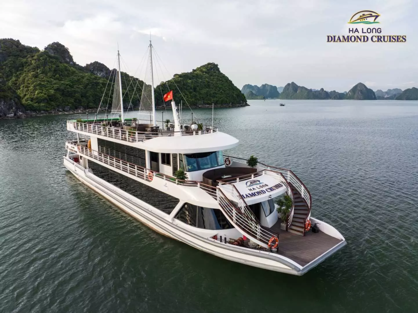 ハロン湾を航行するダイヤモンドデイクルーズ船。「HA LONG DIAMOND CRUISES」のロゴが船首に鮮明に見え、背景の石灰岩の島々と調和の取れた景色を形成しています。