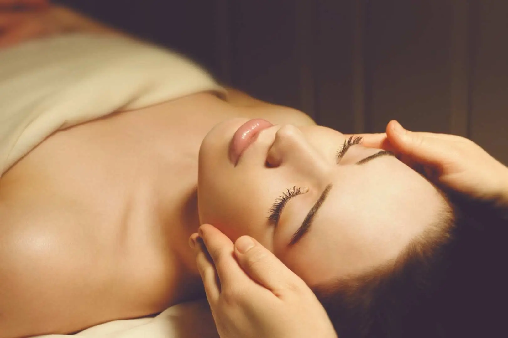 A client at Dermagram Institut Causeway Bay, Hong Kong, enjoying a traditional lymphatic or facial treatment, with a professional therapist gently massaging their sensitive skin for deep relaxation.