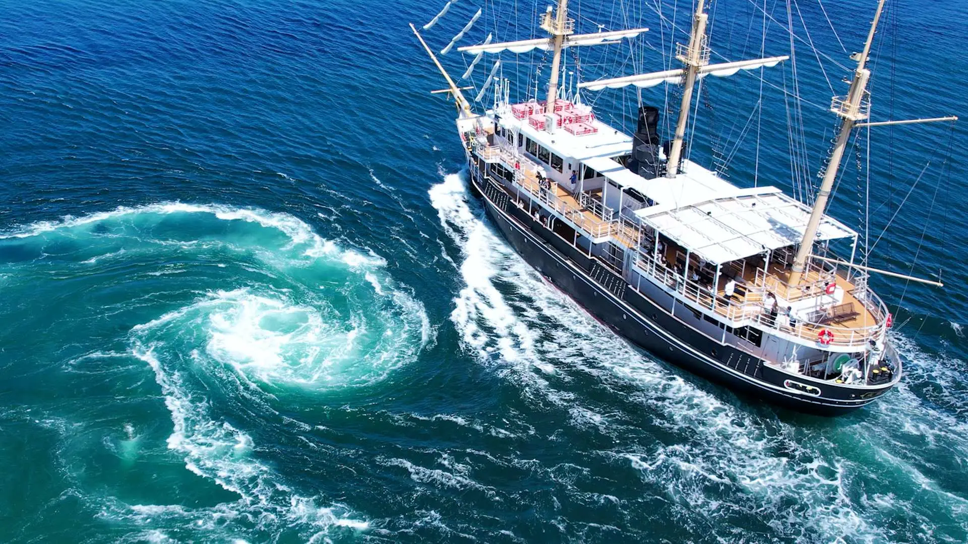 Naruto Strait sightseeing ship closely encountering a massive emerald green whirlpool, highlighting the thrilling natural experience departing from Awaji Island.