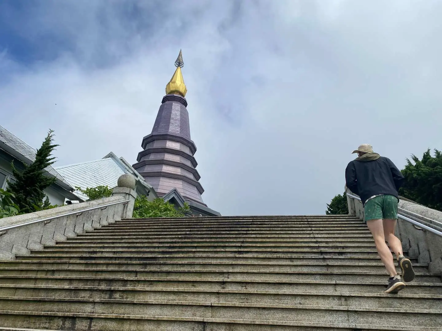 On top of Doi Inthanon, a visitor climbs the majestic stairs leading to the grand Nabhapolbhumisiri Royal Pagoda, experiencing its solemn and sacred ambiance.