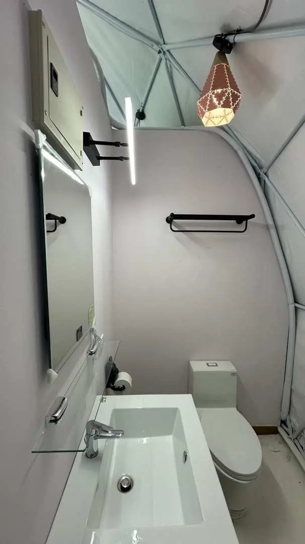 台中新社星空帳內配備的獨立衛浴間，設有現代化洗手台、鏡子和馬桶，提供旅客隱私與便利，享受免搭帳露營的舒適。
