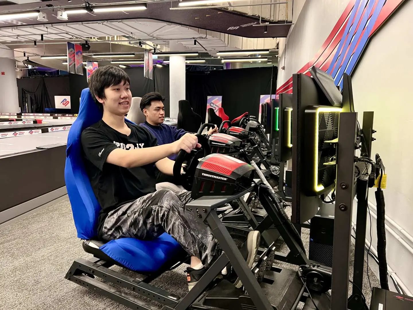 一位年輕男子喺香港Formula Square嘅虛擬賽車模擬器中，專注體驗第一身視角嘅賽車快感，享受獨特嘅實體虛擬結合駕駛樂趣。