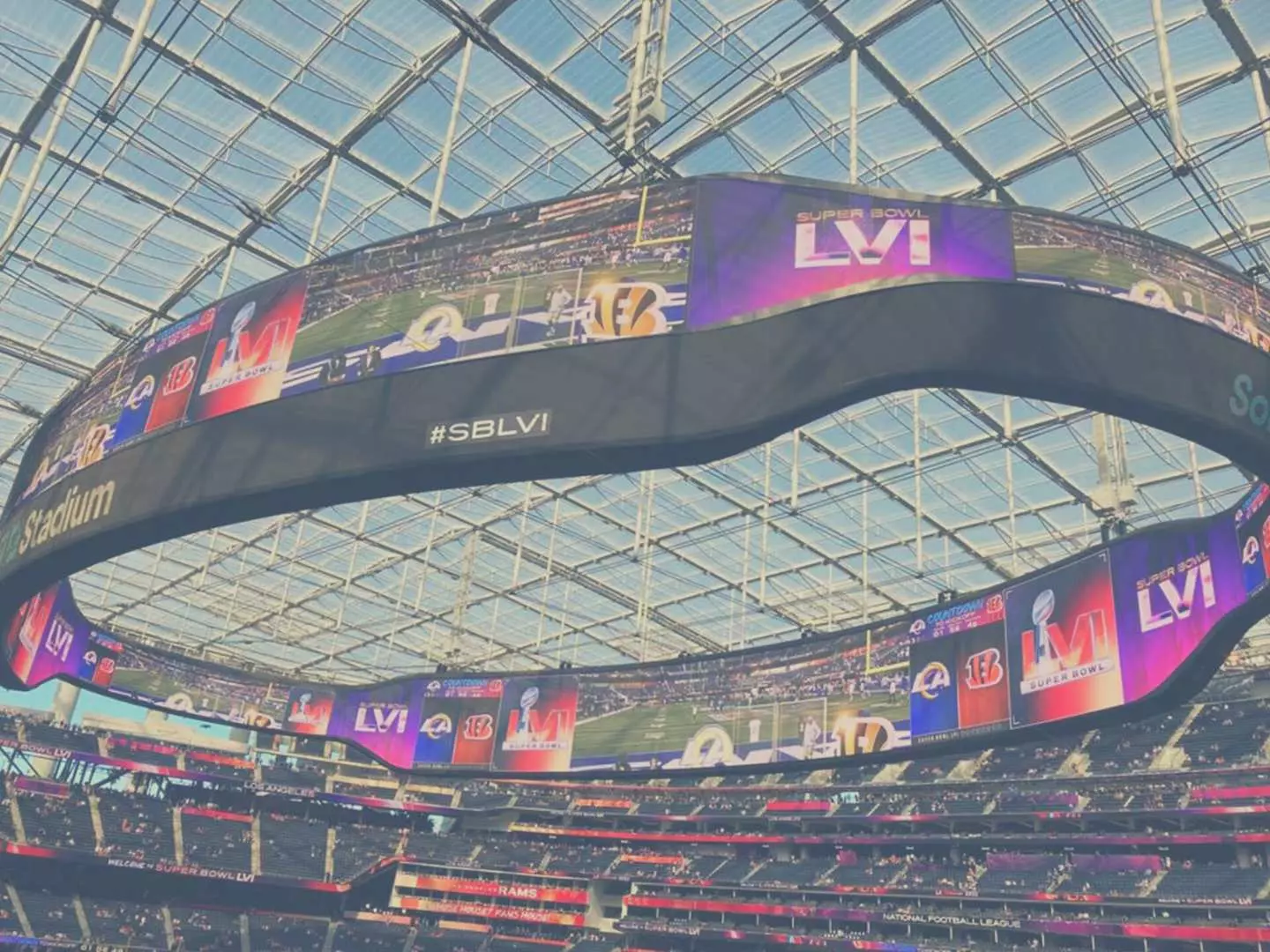 SoFi Stadium's massive Oculus 360-degree circular screen inside, displaying highlights of a Los Angeles Rams NFL game, showcasing the stadium's state-of-the-art facilities.