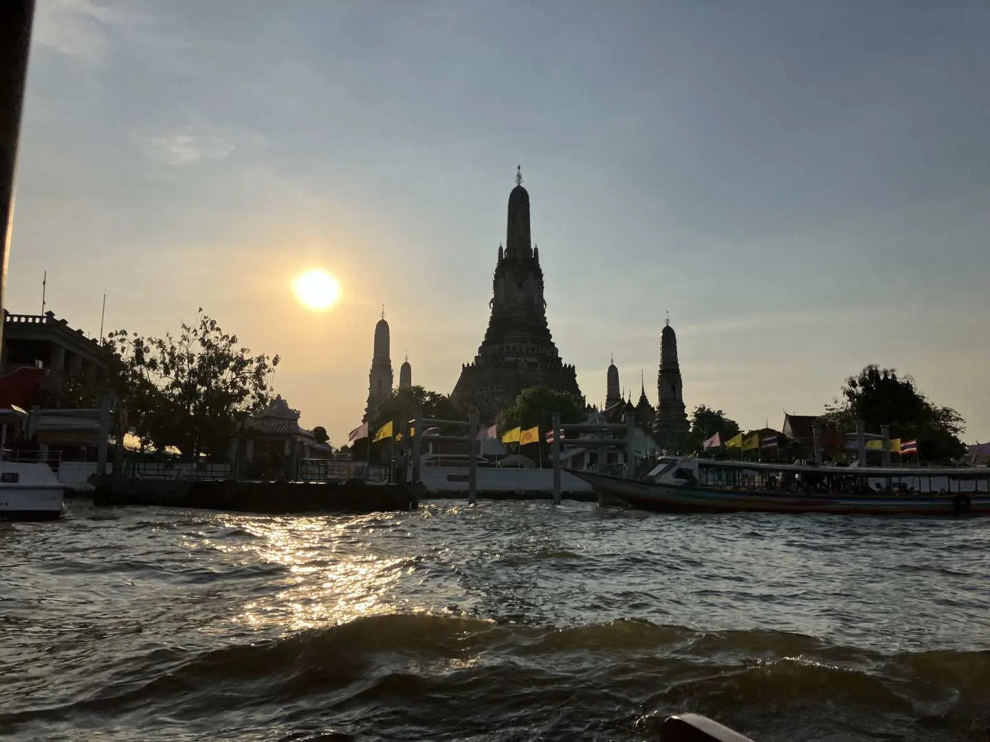 雄偉的鄭王廟在金色的夕陽餘暉下呈現剪影，從昭披耶河上的柚木船上欣賞曼谷景色。