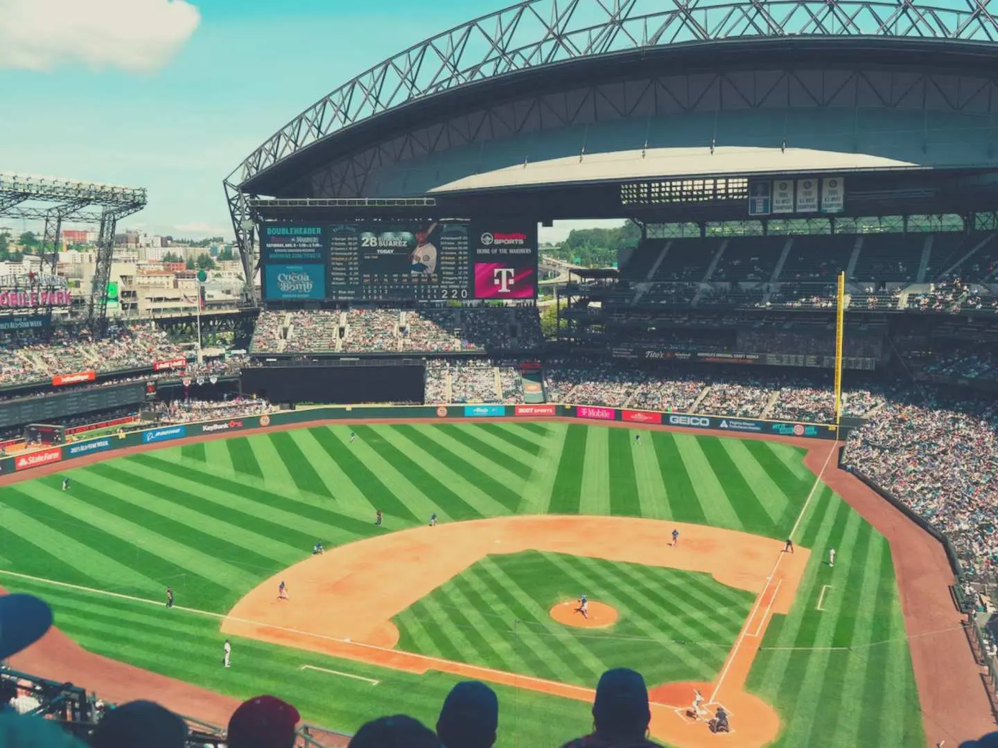 Overhead view of T-Mobile Park, clearly showing the striped green turf, dirt infield, and packed stands, setting the scene for an exciting MLB game.