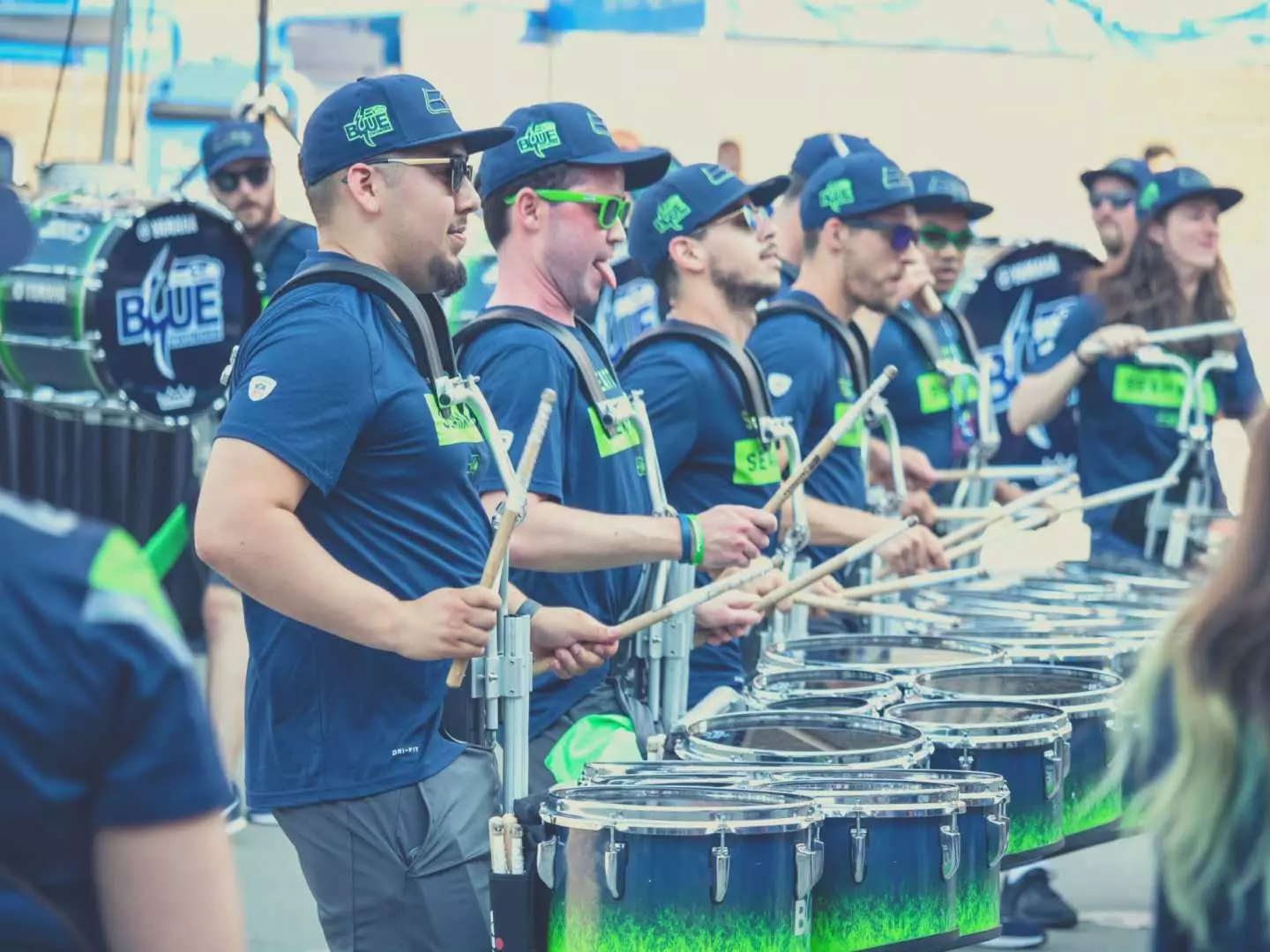 Drummers in Seattle Seahawks team colors perform passionately at Lumen Field, creating a vibrant and energetic NFL game day atmosphere for fans and visitors.