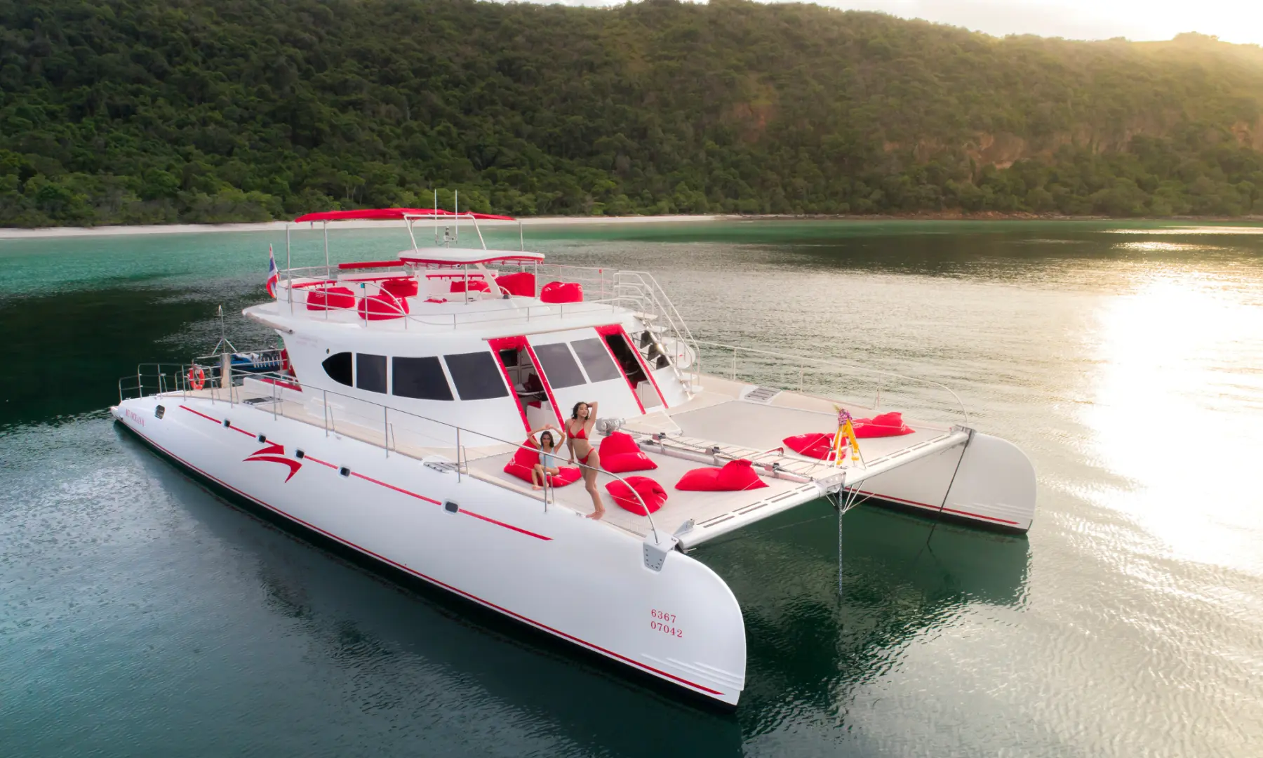 Family enjoying the sun on the front deck of a luxury catamaran yacht in Pattaya, featuring comfortable bean bags, experiencing island exploration.