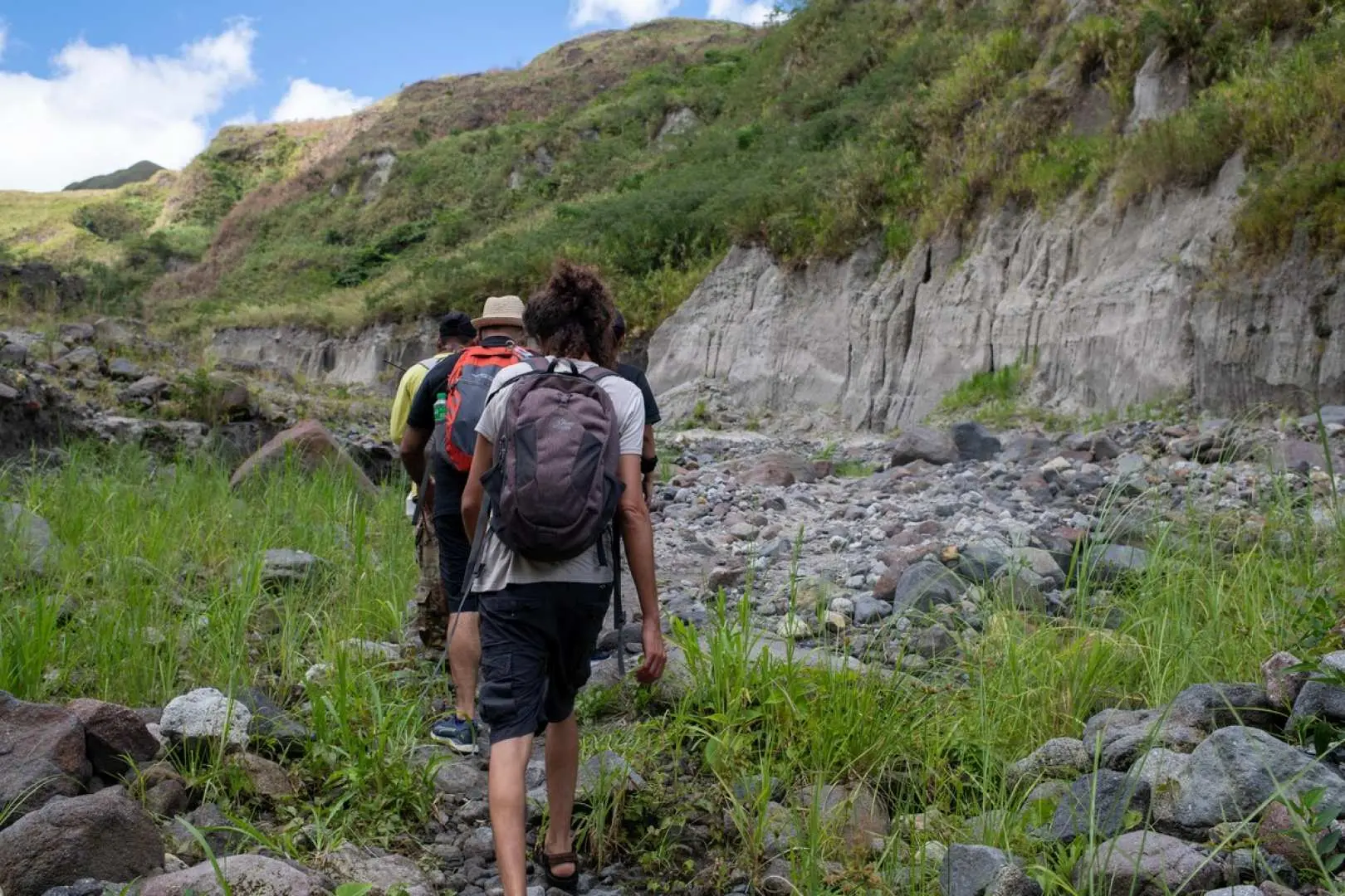 Tourists trekking diligently along the rugged volcanic mud slopes of Mount Pinatubo, experiencing an adventurous journey deep into the volcano.