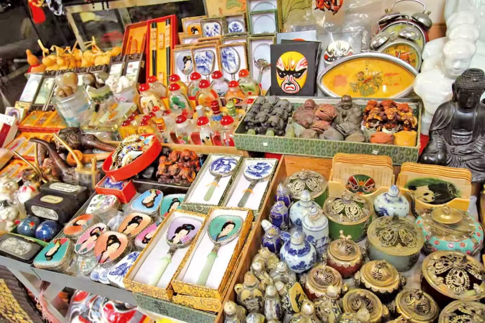 A vibrant display of traditional Chinese antiques and unique souvenirs like Buddha statues and porcelain on a stall in Upper Lascar Row, revealing the joy of treasure hunting.