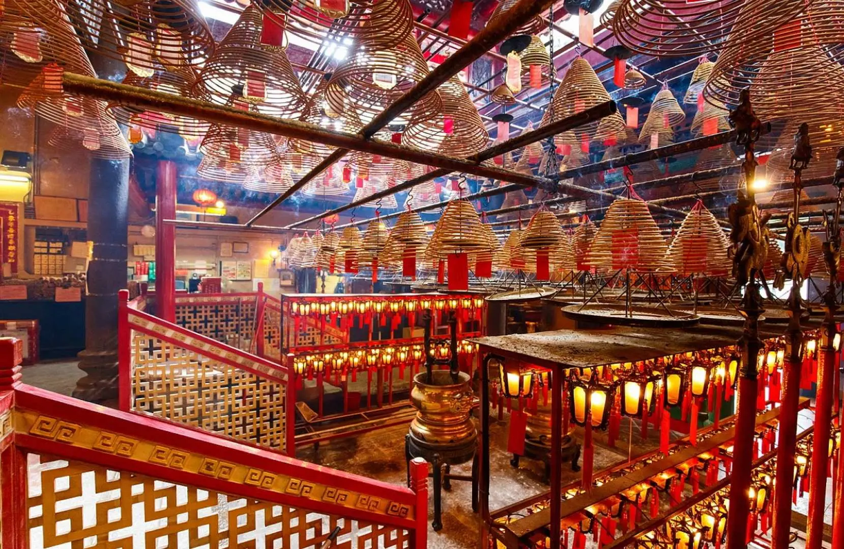 The interior of Hong Kong's Man Mo Temple, with large burning incense coils suspended from the ceiling, creating a sacred and traditional atmosphere for worship.
