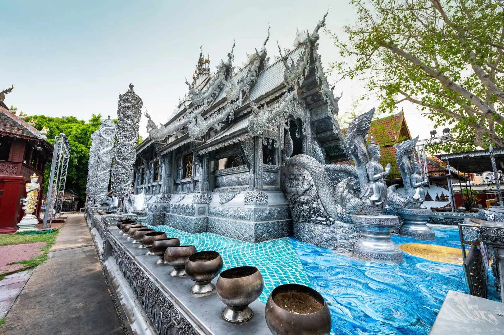 รูปลักษณ์ภายนอกอันงดงามของวัดศรีสุพรรณ (วัดเงิน) ที่มีชื่อเสียงของเชียงใหม่ พร้อมงานแกะสลักเงินวิจิตรและลวดลายซับซ้อนเปล่งประกายภายใต้แสงแดด แสดงถึงศิลปะล้านนาอันเป็นเอกลักษณ์