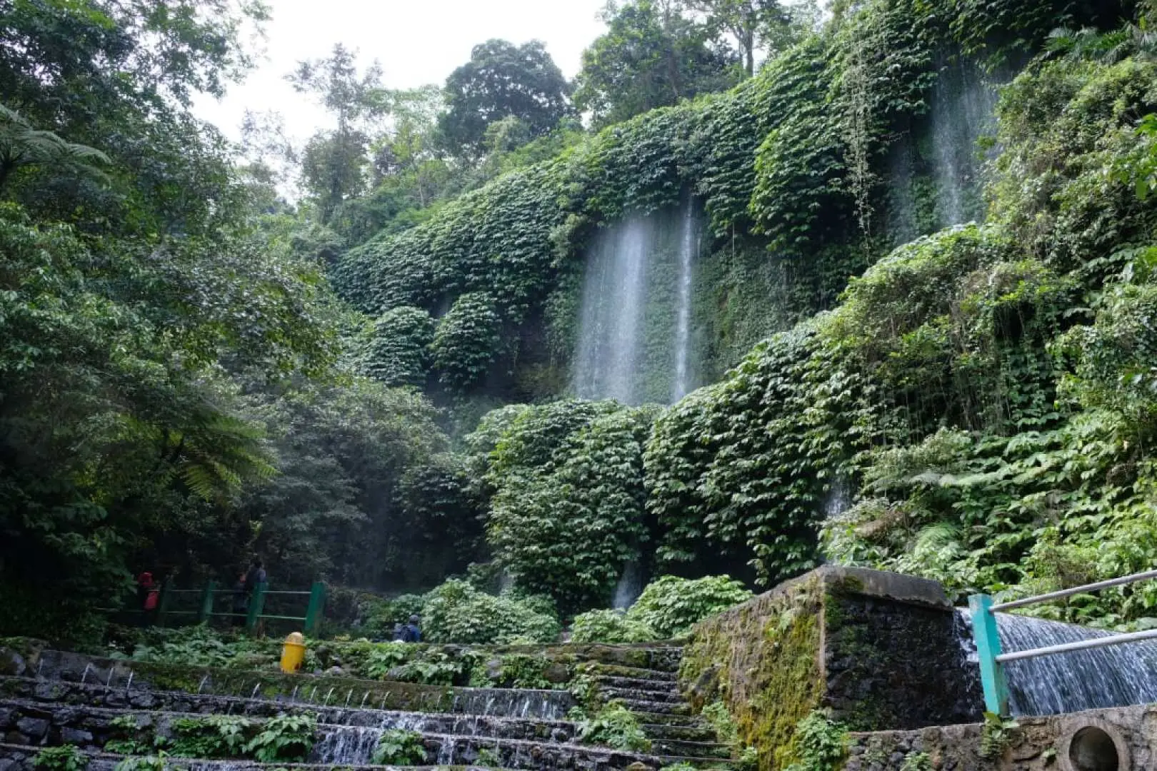 Thác Benang Kelambu ở Lombok, với những dòng nước chảy như rèm hòa quyện vào khu rừng rậm, có những bậc thang và lối đi rõ ràng phía dưới, giúp du khách dễ dàng khám phá kỳ quan thiên nhiên này từ gần.