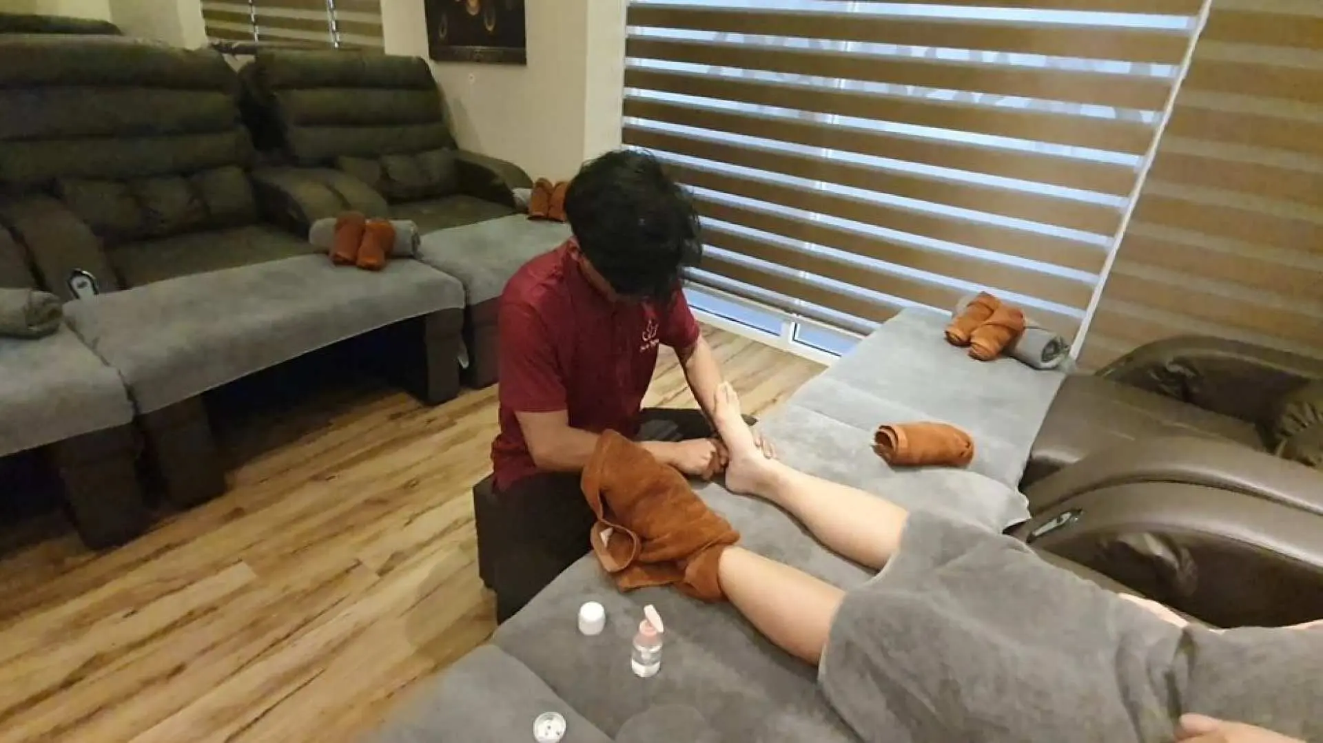 亞庇海洋水療技師在舒適躺椅上為客人進行放鬆足部按摩，突顯專業護理和足部按摩套餐。