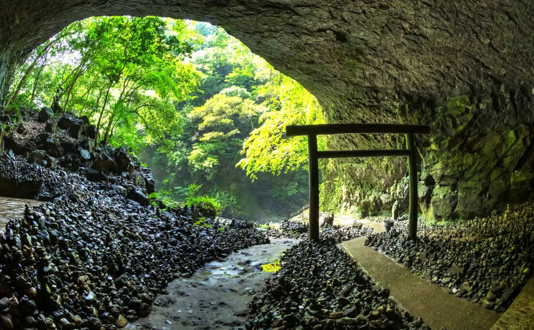 Hang động thần bí Amano Yasugawara (天安河原) ở Miyazaki, với cổng torii ở lối vào, dòng suối chảy qua và vô số đá ước nguyện được du khách xếp chồng lên nhau, mang đậm màu sắc thần thoại.