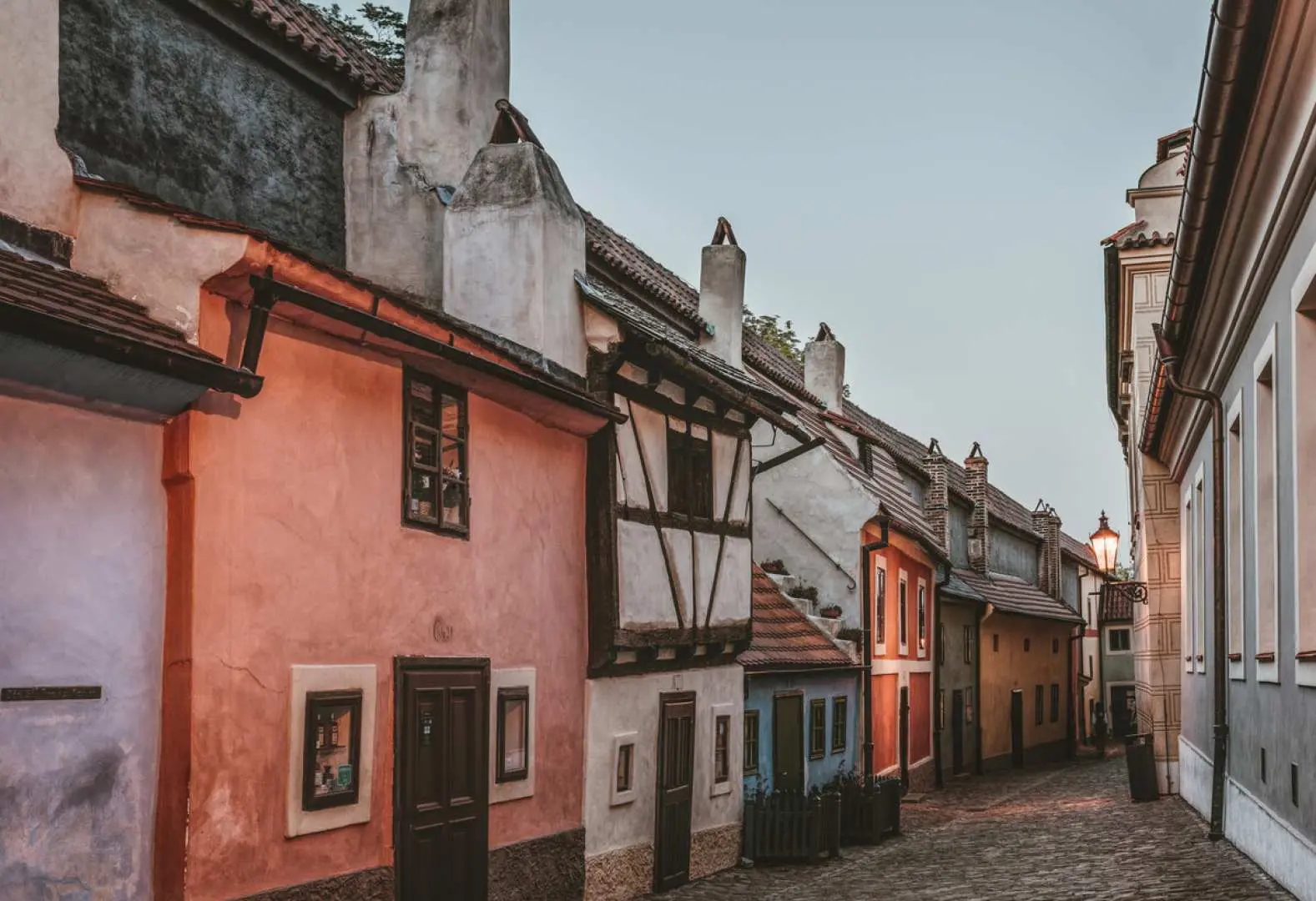 Charming narrow cobblestone street in Prague's historic district, lined with colorful traditional houses featuring unique architectural details, inviting exploration with the Go City Pass.