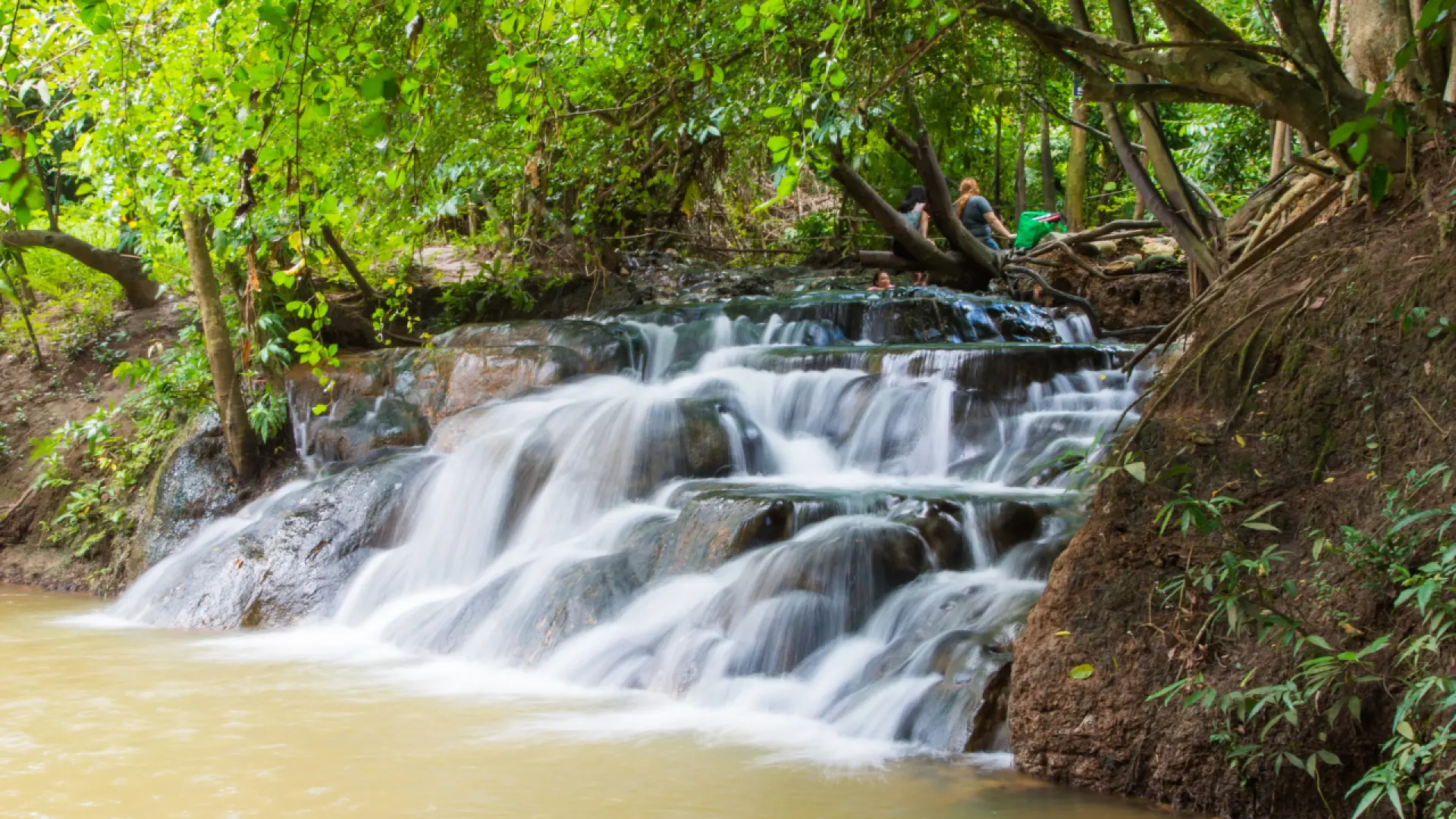 Krabi Hot Spring Waterfall, a series of natural thermal cascades gently flowing over rocks, surrounded by lush tropical rainforest, offering a unique relaxing experience in nature.
