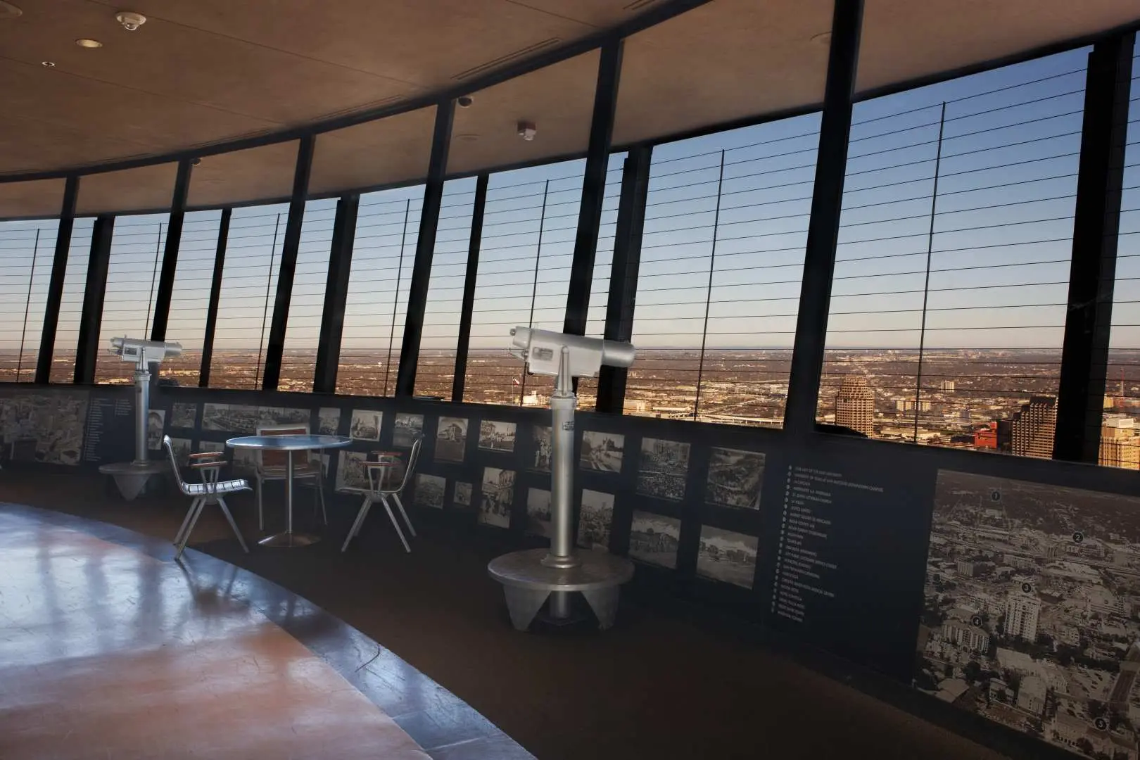 Visitors at the Tower of the Americas observation deck in San Antonio use telescopes to view the panoramic city skyline, offering a unique high-altitude perspective with CityPASS®.