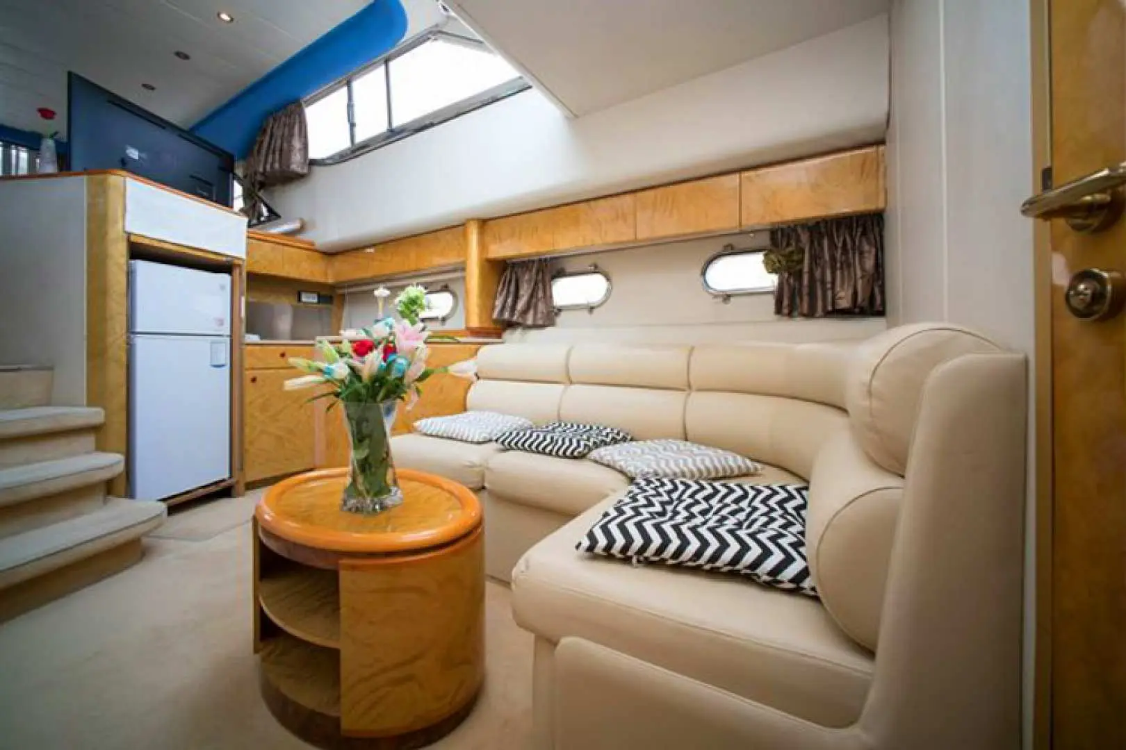 The comfortable interior living room of a luxury private yacht, featuring a spacious sofa and coffee table, offering a private and relaxing space to enjoy the Han River scenery.