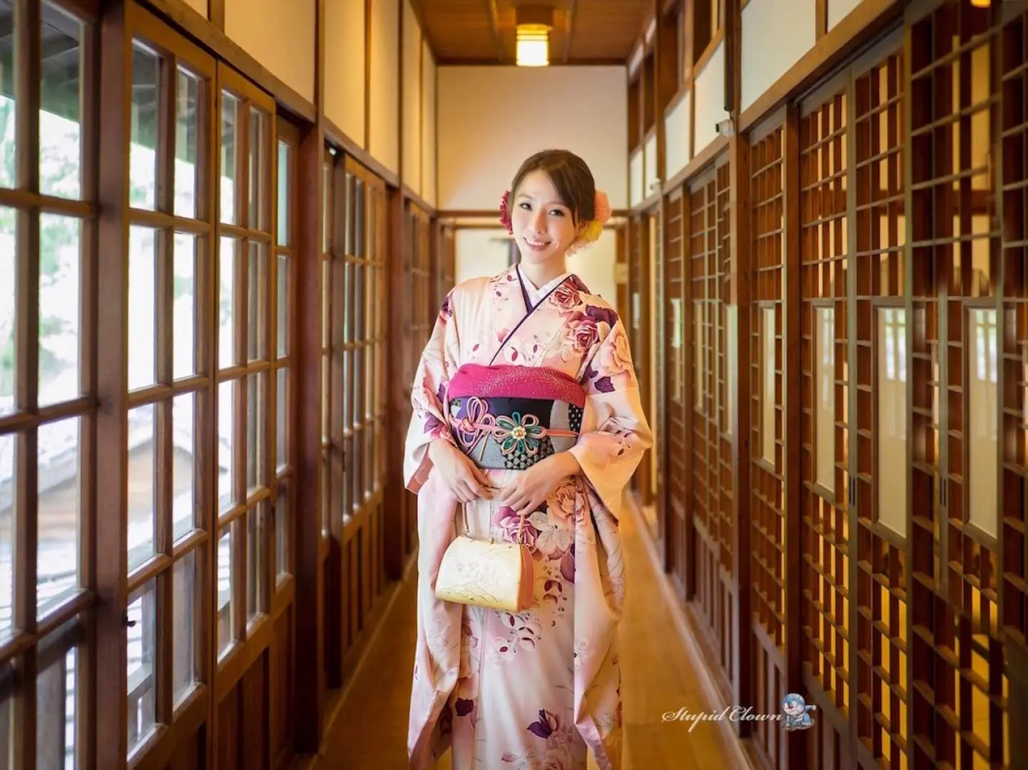 板橋優花梨和服租借，女子身穿粉色花紋和服，手提優雅小包，漫步於日式木造長廊，展現溫婉氣質。