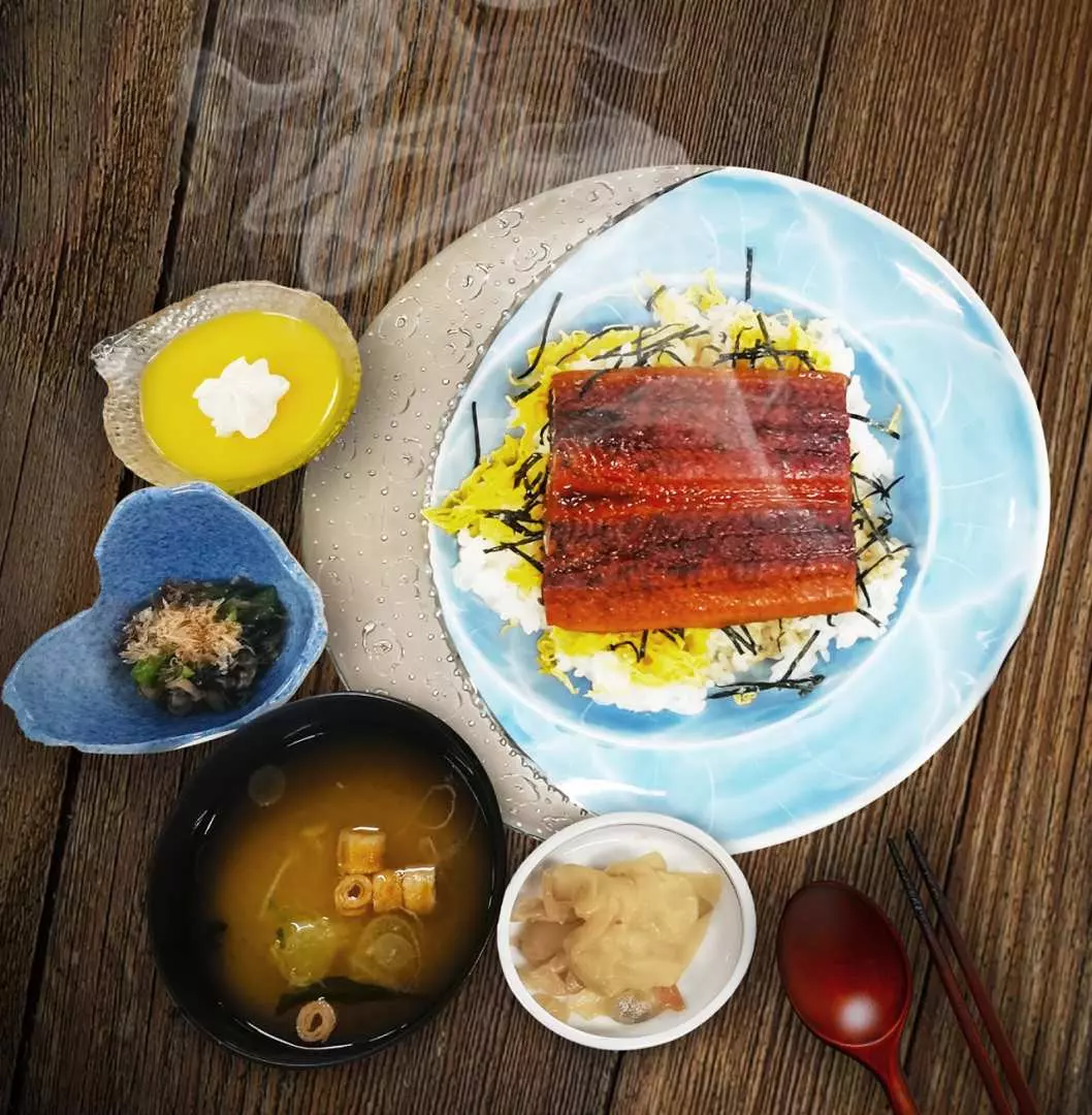 A delectable Japanese set meal featuring grilled eel over rice (Unadon), with miso soup, pickles, and dessert, showcasing local Izu Onsen Street cuisine.