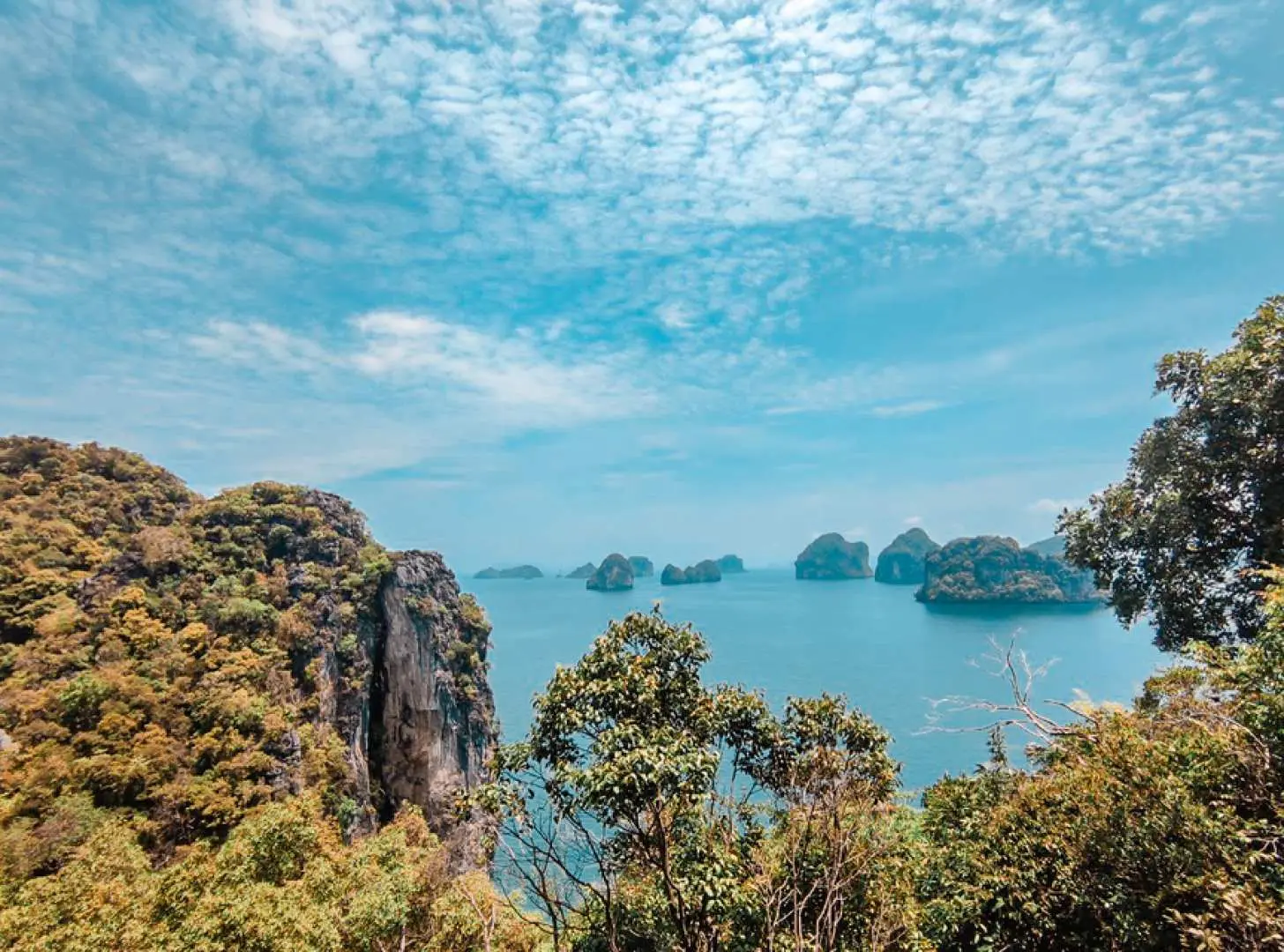 Panoramic view of Phang Nga Bay from a high vantage point in Phuket, with countless lush limestone islets dotting the calm blue sea.