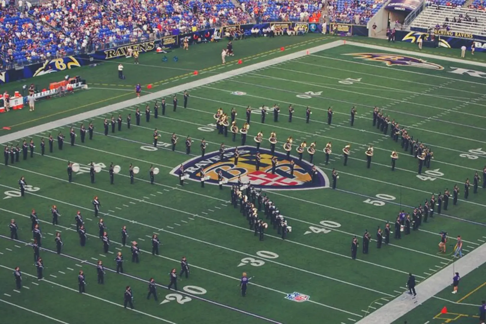 Exciting halftime show during an NFL game at M&T Bank Stadium, with a large marching band performing spectacularly on the field, creating a vibrant atmosphere for fans.