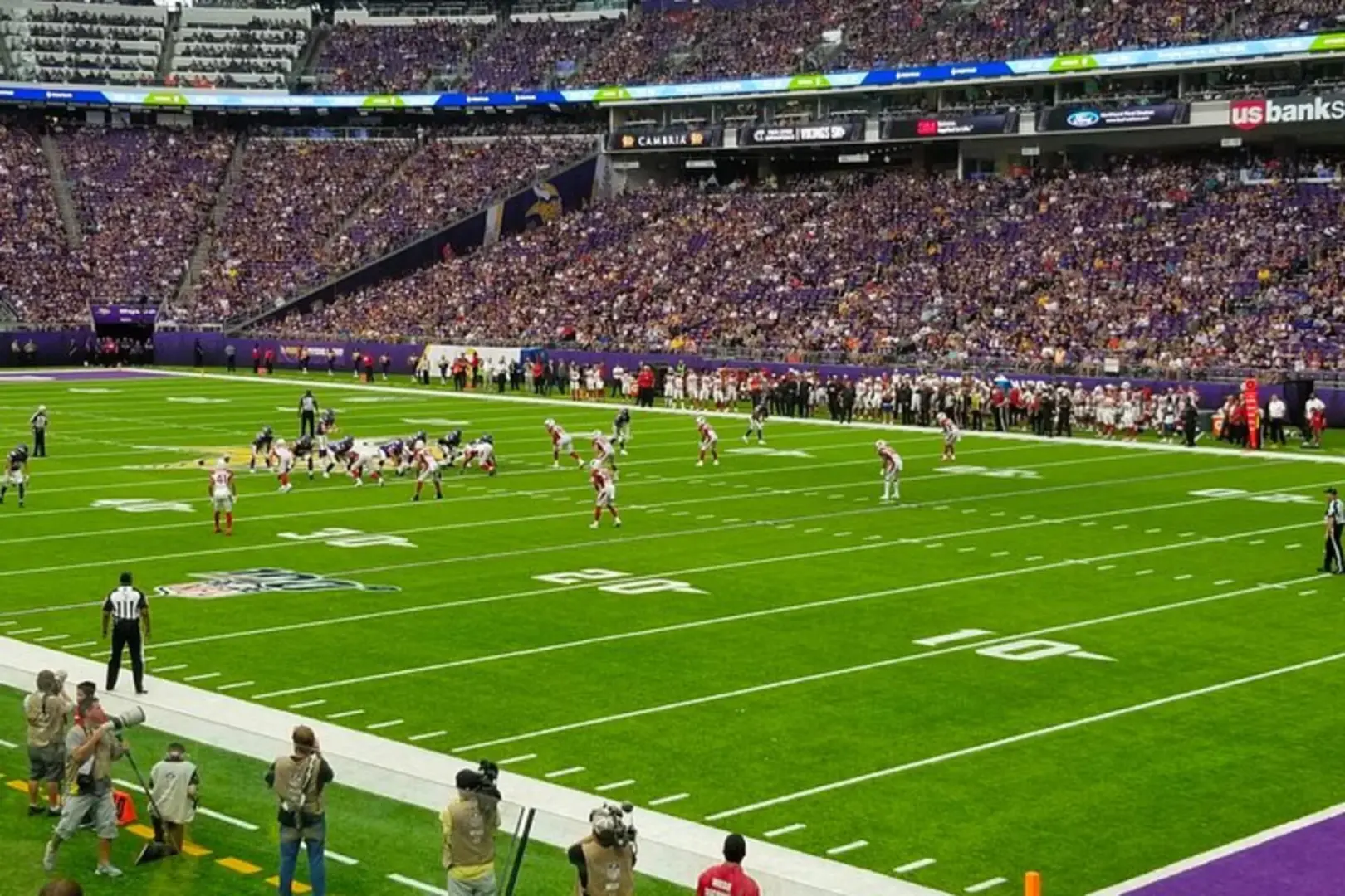 Close-up shot capturing the intense offense and defense of Minnesota Vikings NFL players during a game at US Bank Stadium, conveying the high tension and excitement of the match.