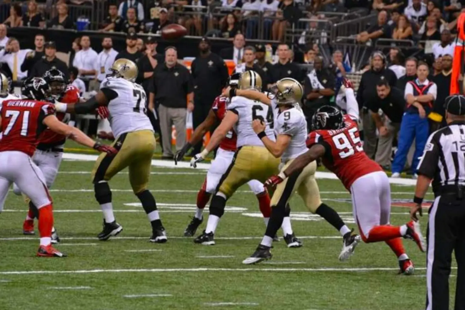 Intense game action during an NFL New Orleans Saints football match inside the Caesars Superdome, with players clashing on the field.