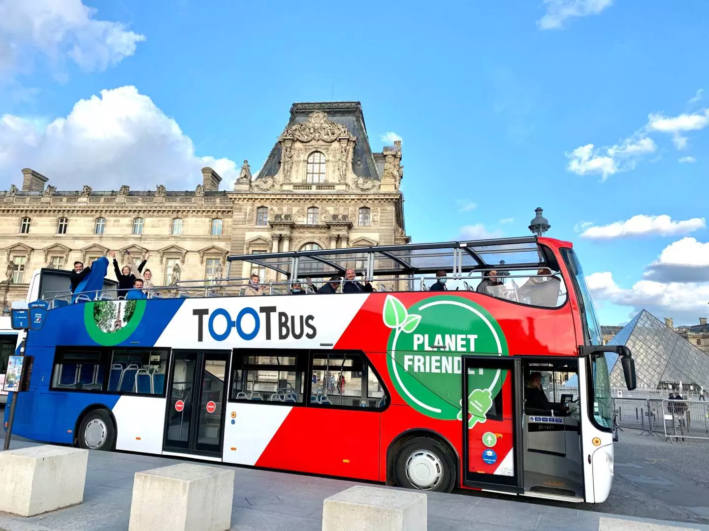 TOOTBUS随上随下观光巴士停靠在历史悠久的卢浮宫和金字塔附近，准备载送游客前往巴黎景点。