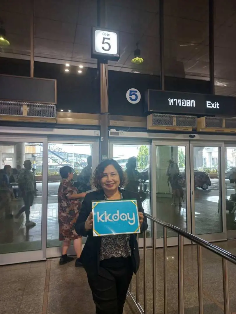 KKday 직원이 공항 도착 5번 게이트에서 환영 팻말을 들고, 파타야로 향하는 개인 전용 차량을 예약한 고객들을 맞이할 준비를 하고 있습니다.