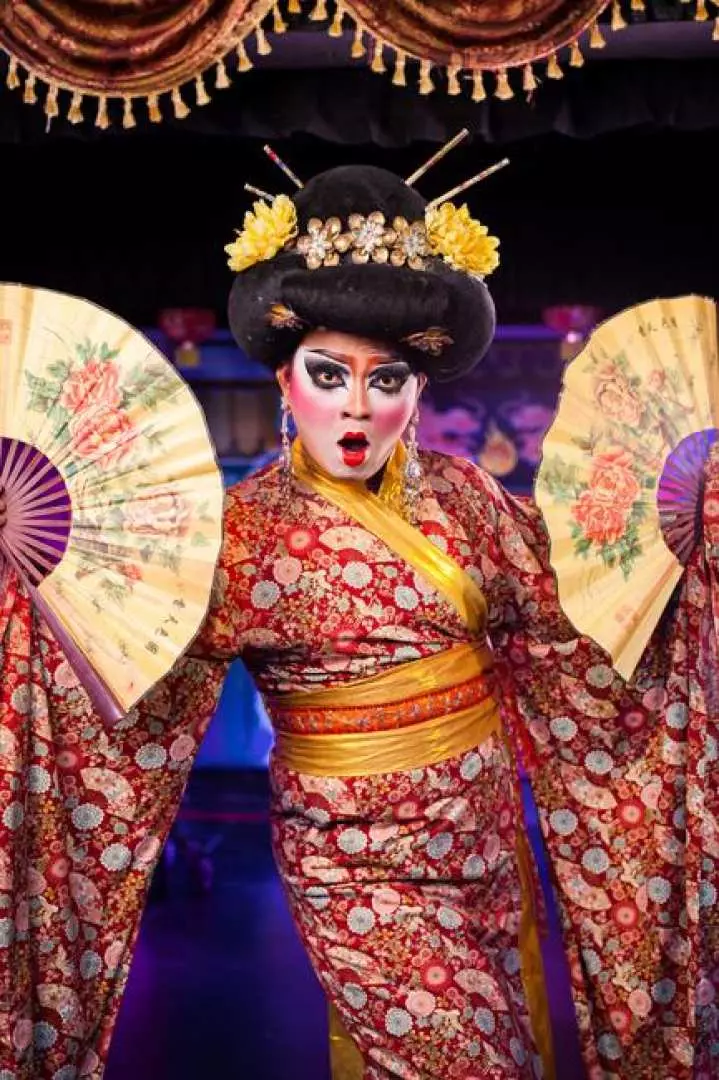 ภาพระยะใกล้ของนักแสดงจากคาบาเร่ต์โชว์บลู ดราก้อน กระบี่ สวมชุดกิโมโนสไตล์เกอิชาญี่ปุ่นอันประณีต แต่งหน้าจัดเต็ม และสวมเครื่องประดับศีรษะอันวิจิตร ถือพัดตกแต่ง