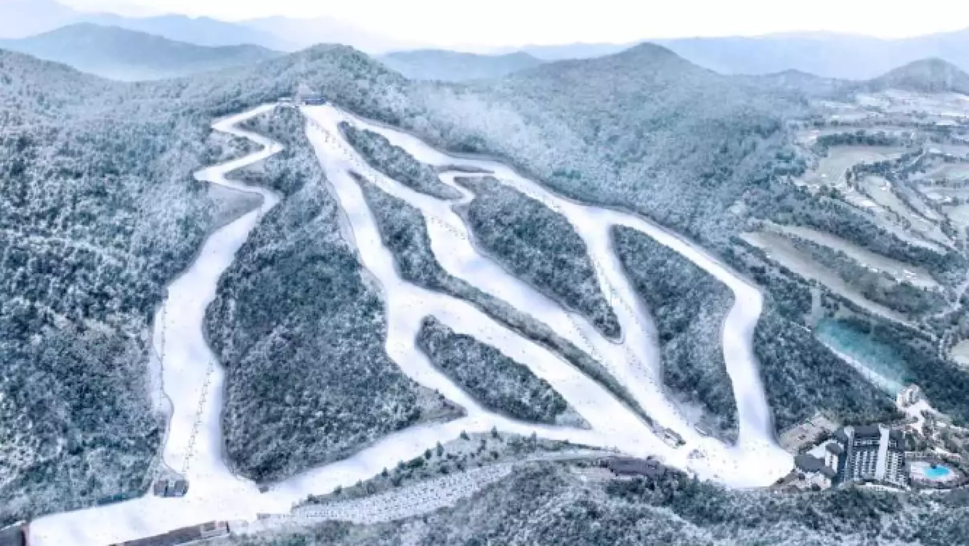 Breathtaking aerial panoramic view of Elysian Gangchon Ski Resort, clearly showing multiple winding ski runs and the surrounding snow-covered mountainous landscape.