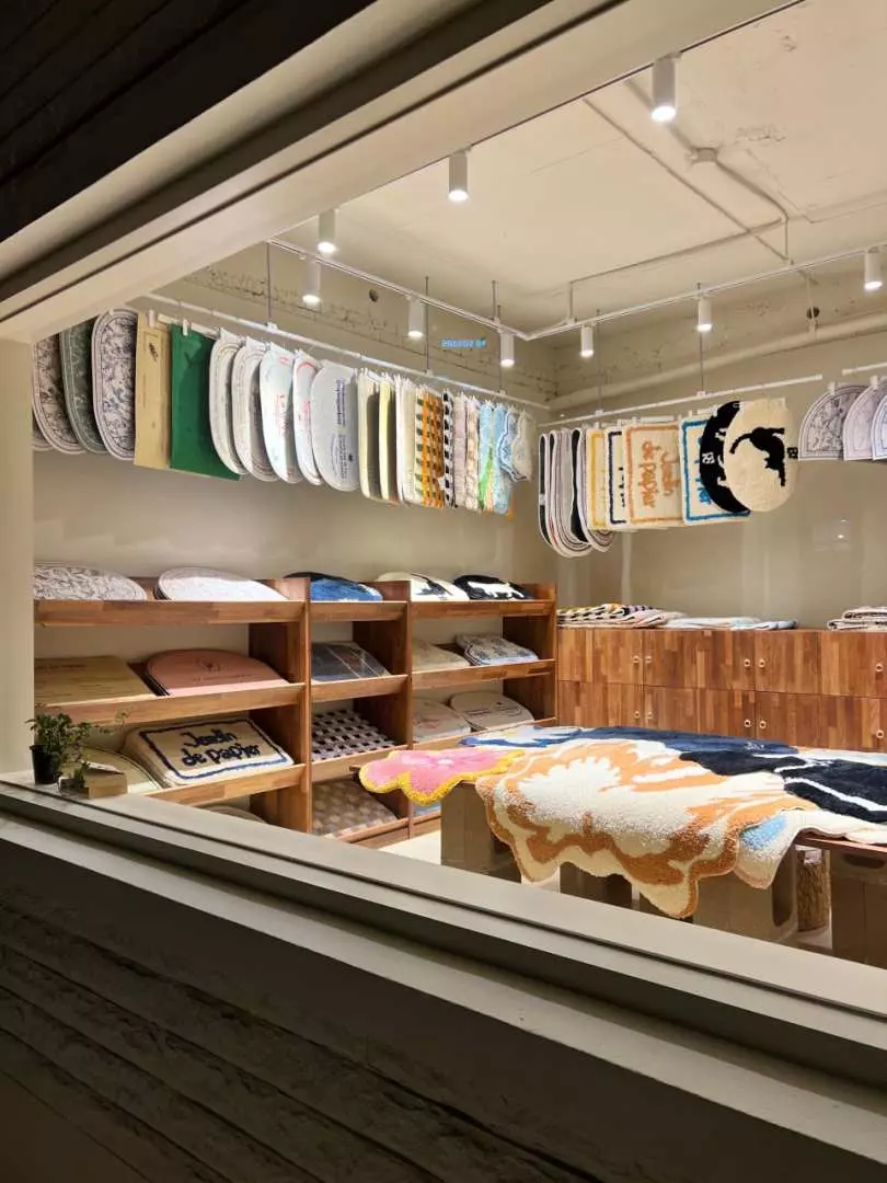 透过玻璃窗看见釜山全浦斋街的潮流精品店内部，展示着各式独特服饰、配件与文创商品，营造时尚氛围。
