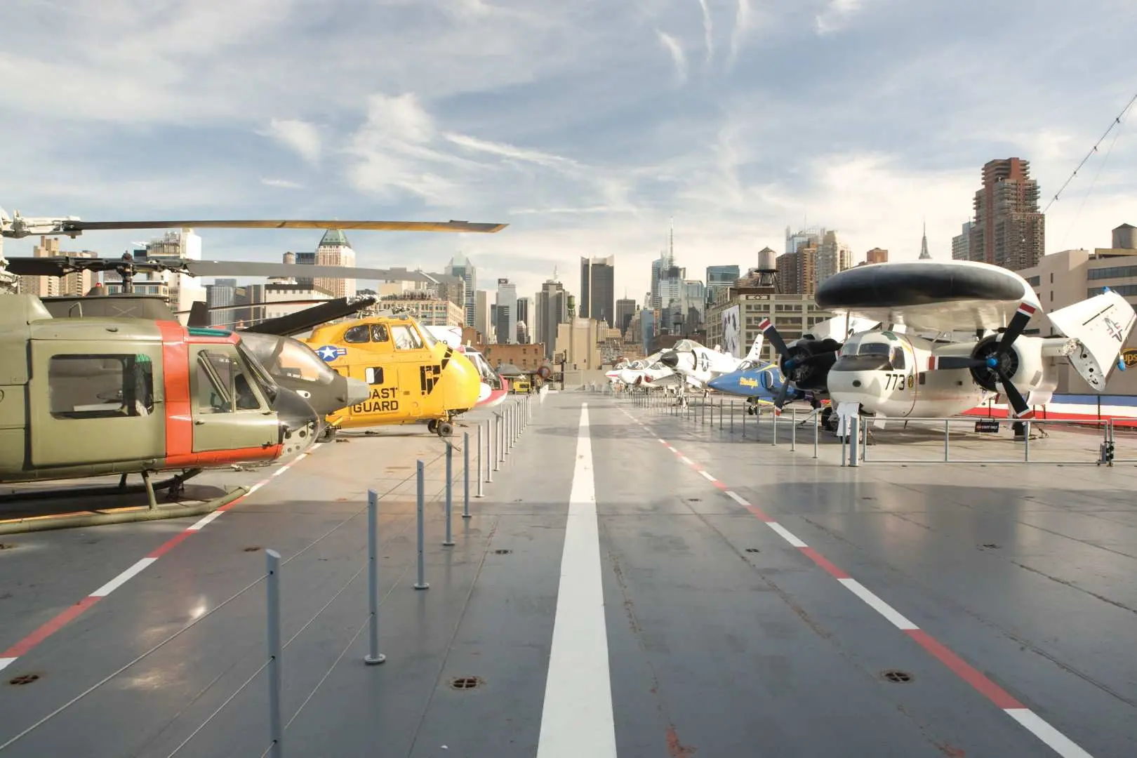 紐約無畏號博物館航空母艦甲板上，展示多架經典戰鬥機和直升機，背景是壯麗的紐約城市天際線。