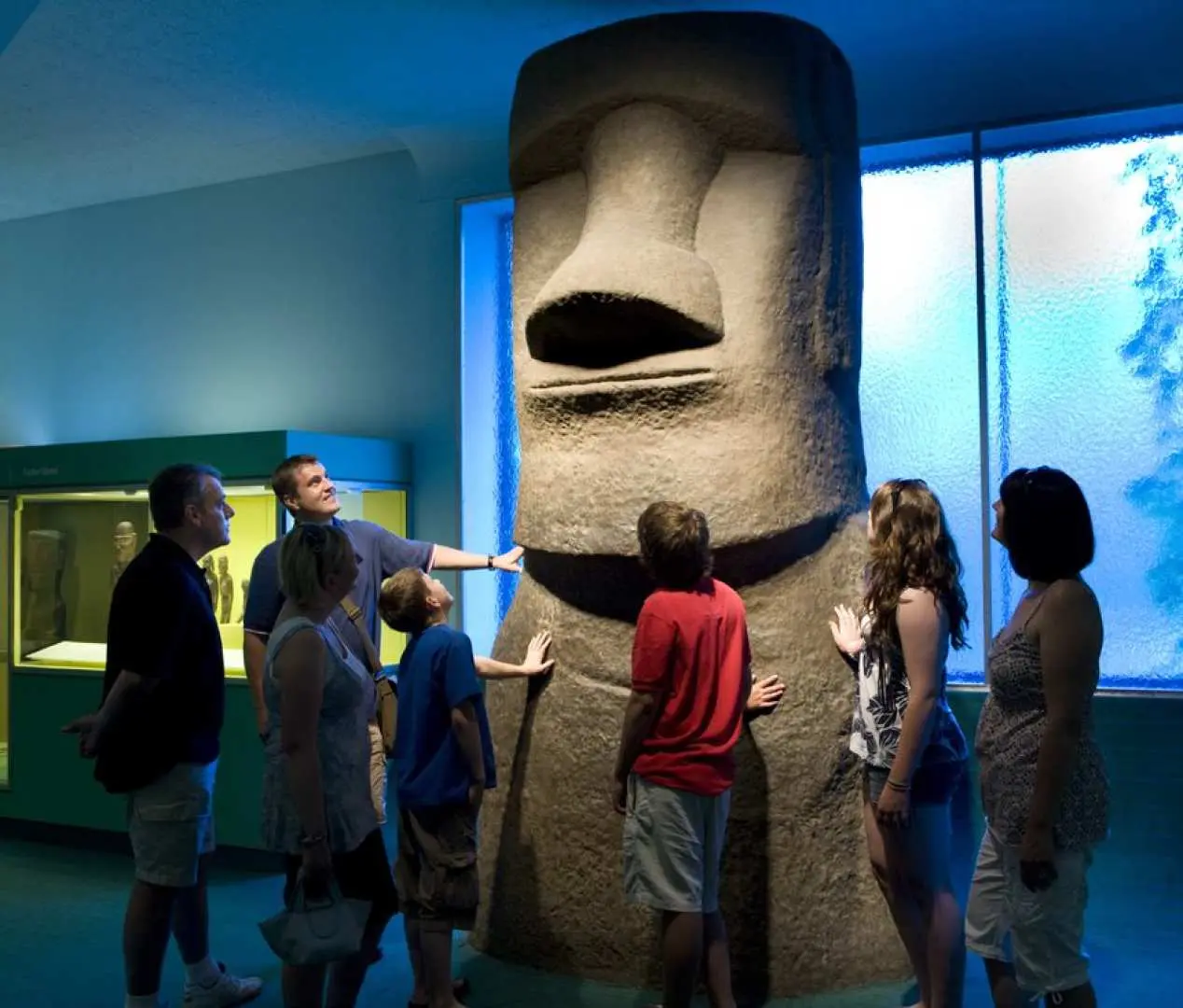 Visitors at the American Museum of Natural History marveling at the colossal Easter Island Moai statue, exploring ancient civilizations and global cultures.