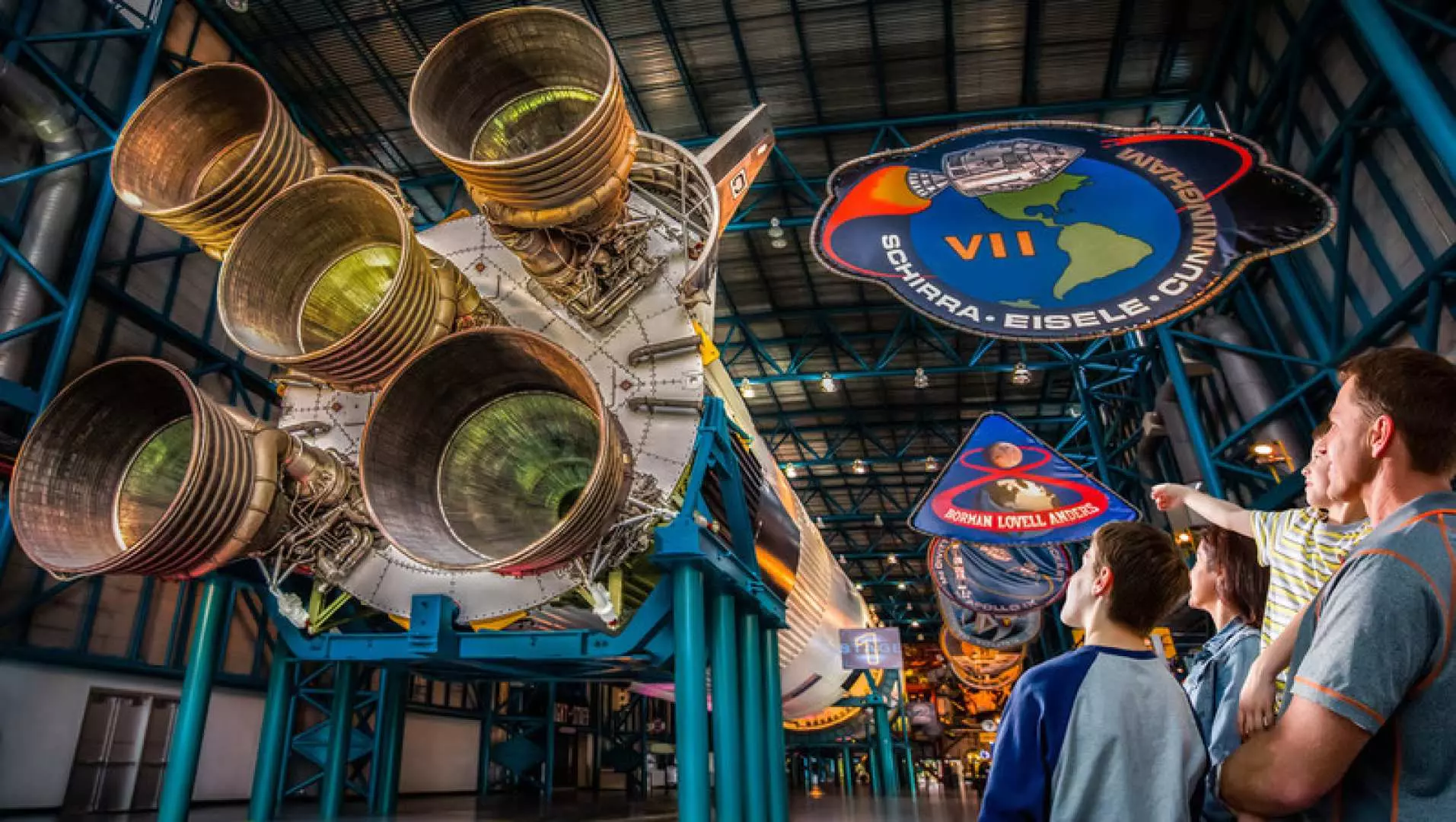 Visitors admiring the colossal Saturn V rocket display at Kennedy Space Center Visitor Complex, experiencing iconic space exploration history with the Orlando All-Inclusive Pass.