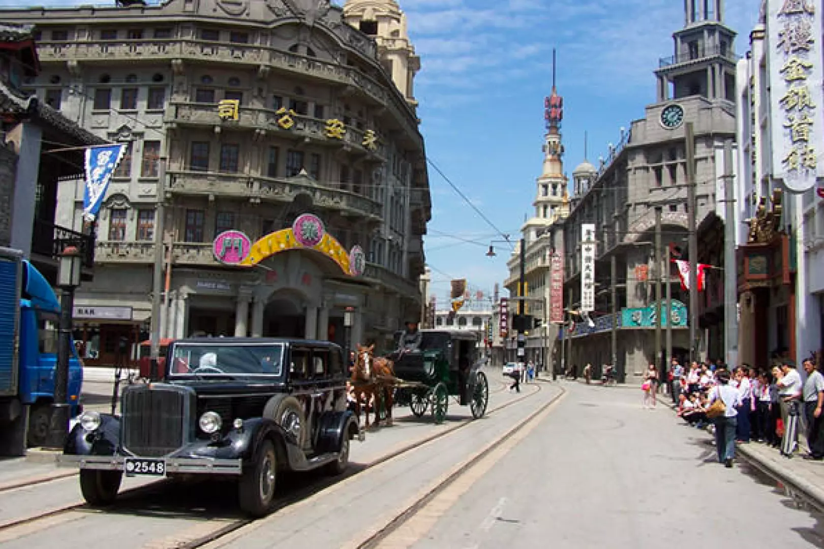 Vintage cars and horse carriages on a bustling replica street at Shanghai Film Park, recreating the vibrant atmosphere of 1930s Shanghai's Nanjing Road, perfect for cultural exploration.