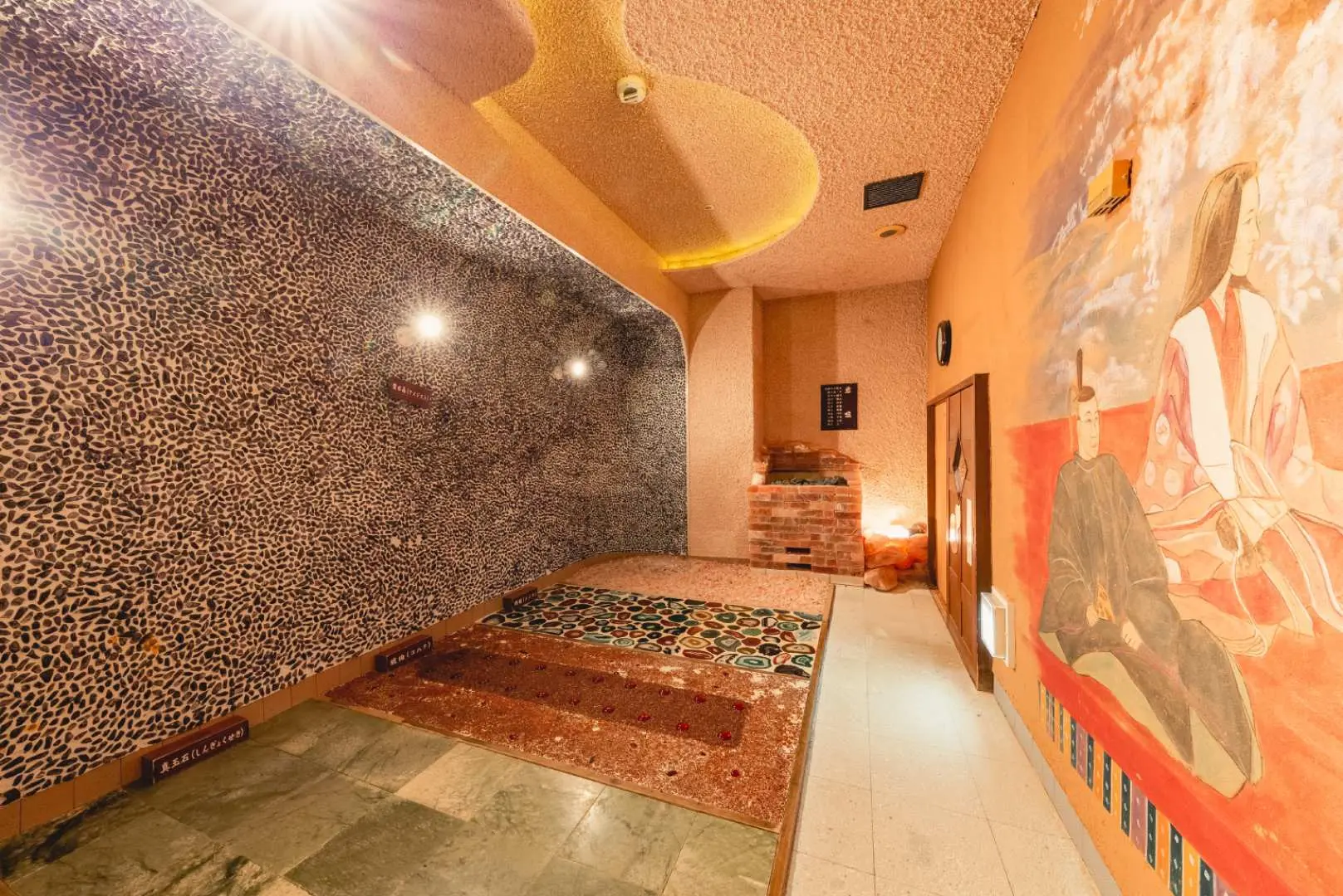 Carefully designed Japanese-style relaxation space inside Taikou no Yu, with pebble walls and historical murals, offering a serene area to unwind after bathing.
