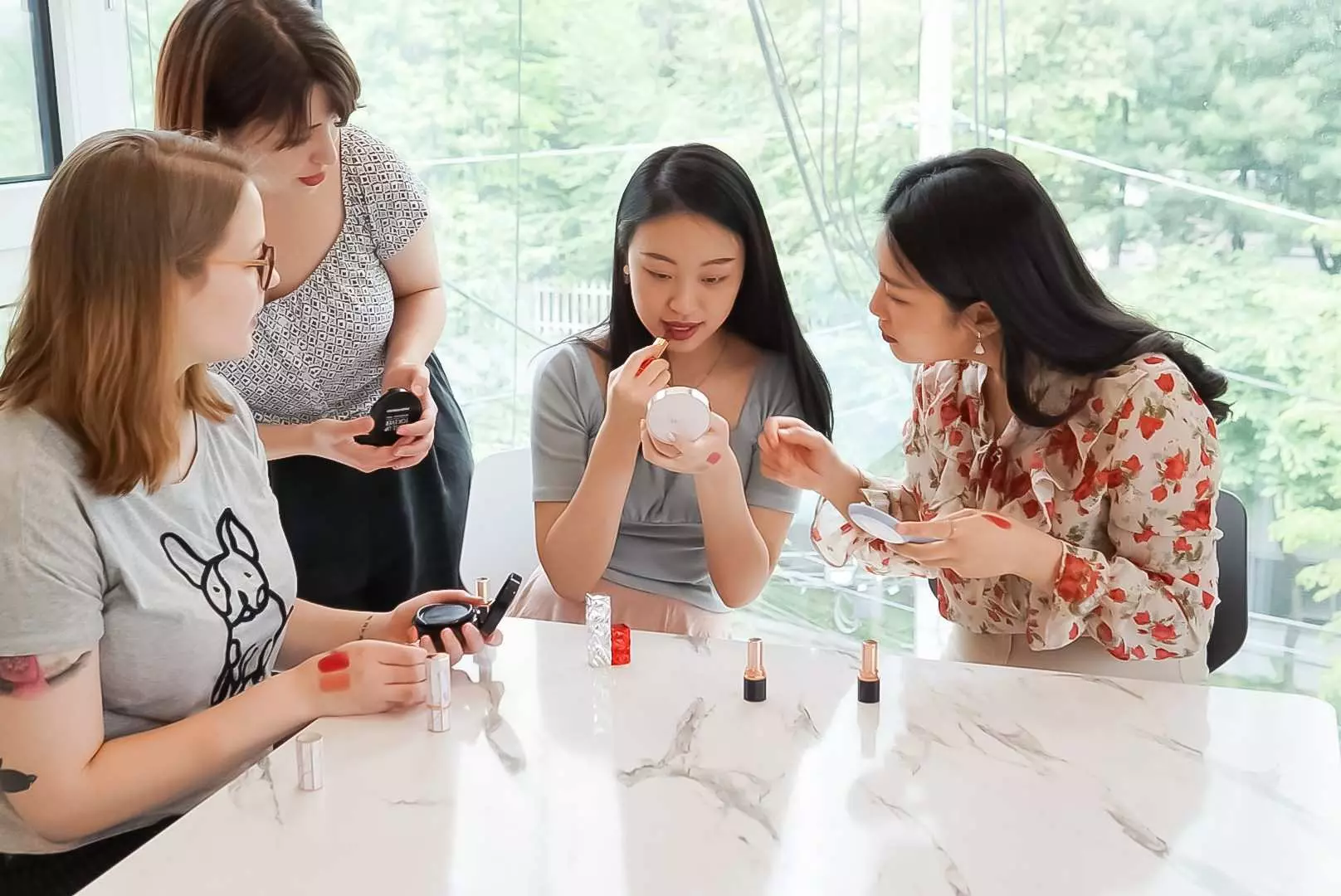 In a Korean beauty DIY class, participants assist each other in trying out handmade lipsticks and skincare products, enjoying the personalized beauty experience from customized items.