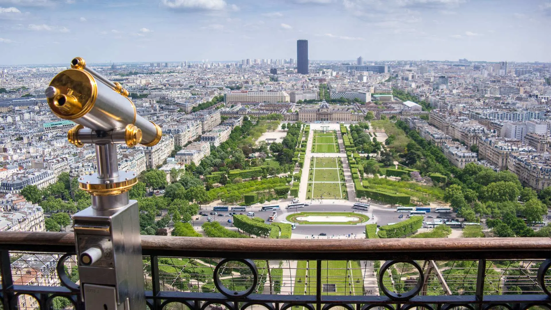 從艾菲爾鐵塔觀景台俯瞰戰神廣場與巴黎市景，前景有金屬望遠鏡，讓遊客體驗壯麗的城市全景。
