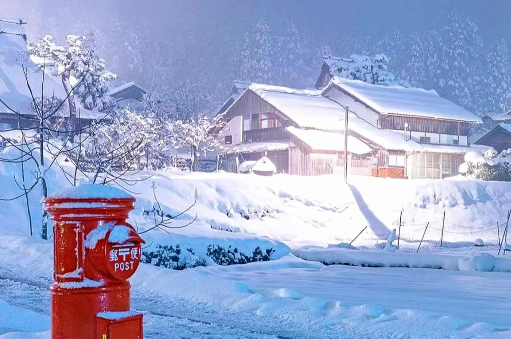 日本美山茅葺之里合掌村冬日雪景，紅色傳統郵筒被白雪覆蓋，背景是積雪的茅草屋與樹林，陽光灑落，寧靜溫馨。