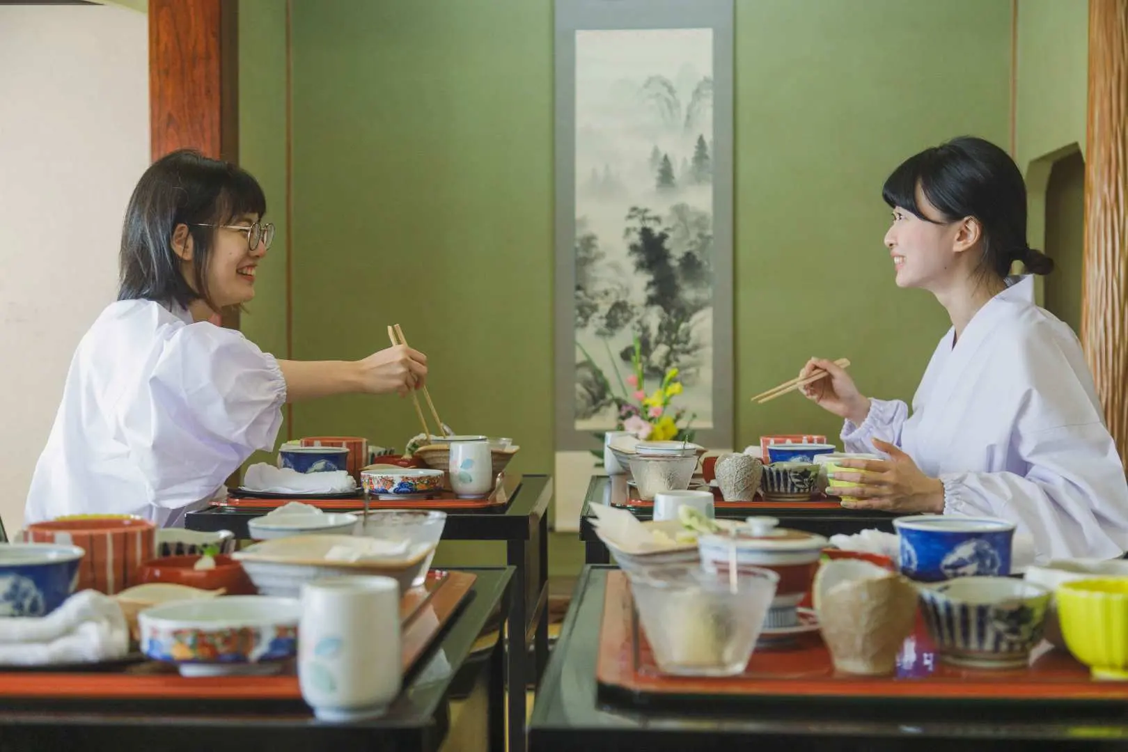 Two participants in white robes enjoying traditional shojin ryori (Buddhist vegetarian cuisine) at Yamagata's Jionji Temple, experiencing the tranquil temple diet as part of the spiritual culture tour.