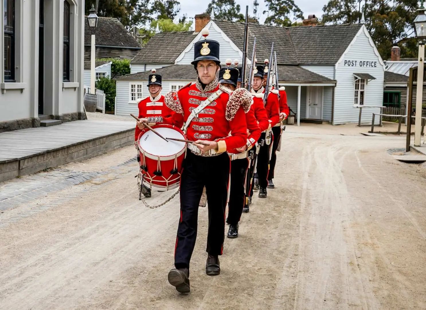 Sovereign Hill Redcoat parade in Melbourne, featuring soldiers in grand 19th-century uniforms with drums and rifles marching on a historical street, recreating a spectacular gold rush era scene.