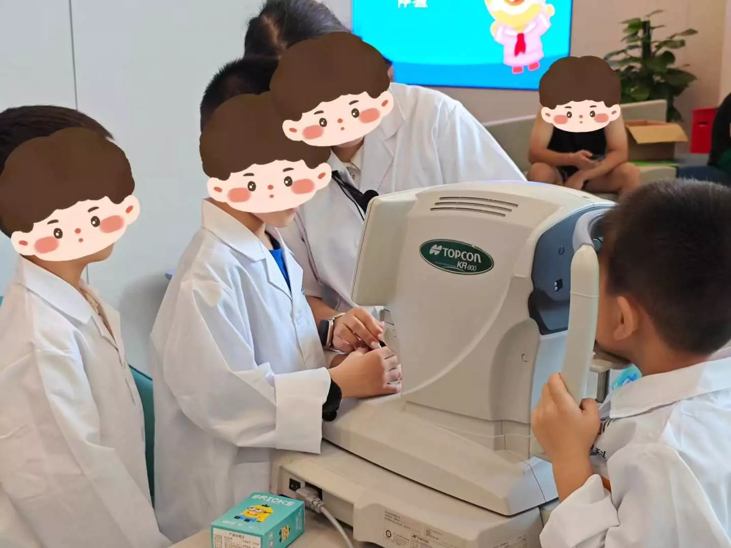 Trải nghiệm nghề nghiệp cho trẻ em ở Thâm Quyến, các bác sĩ mắt nhỏ mặc áo blouse trắng, dưới sự hướng dẫn của chuyên gia, sử dụng thiết bị nhãn khoa để trải nghiệm quá trình kiểm tra thị lực.